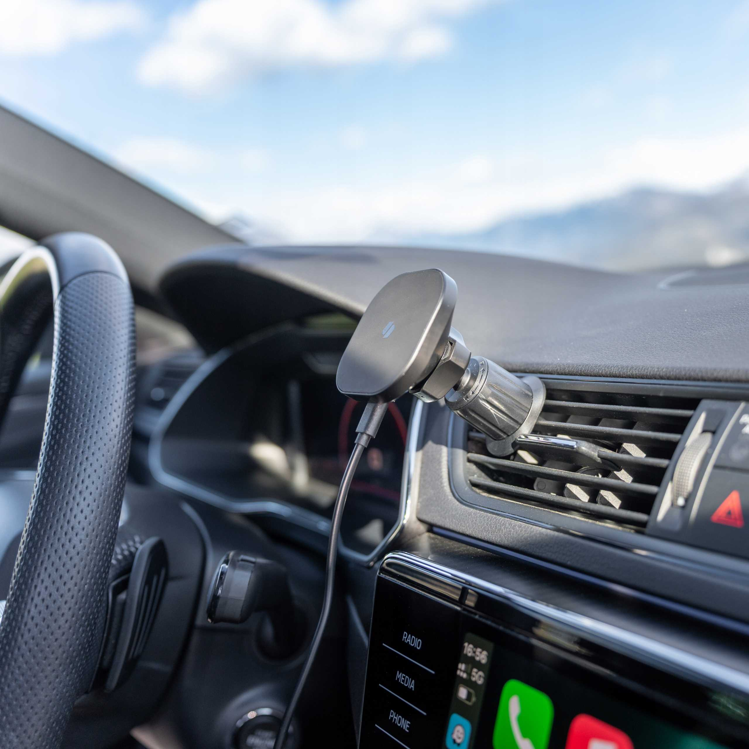 Widok wnętrza samochodu. Kierownica po lewej, uchwyt na telefon pośrodku i deska rozdzielcza z ekranem.