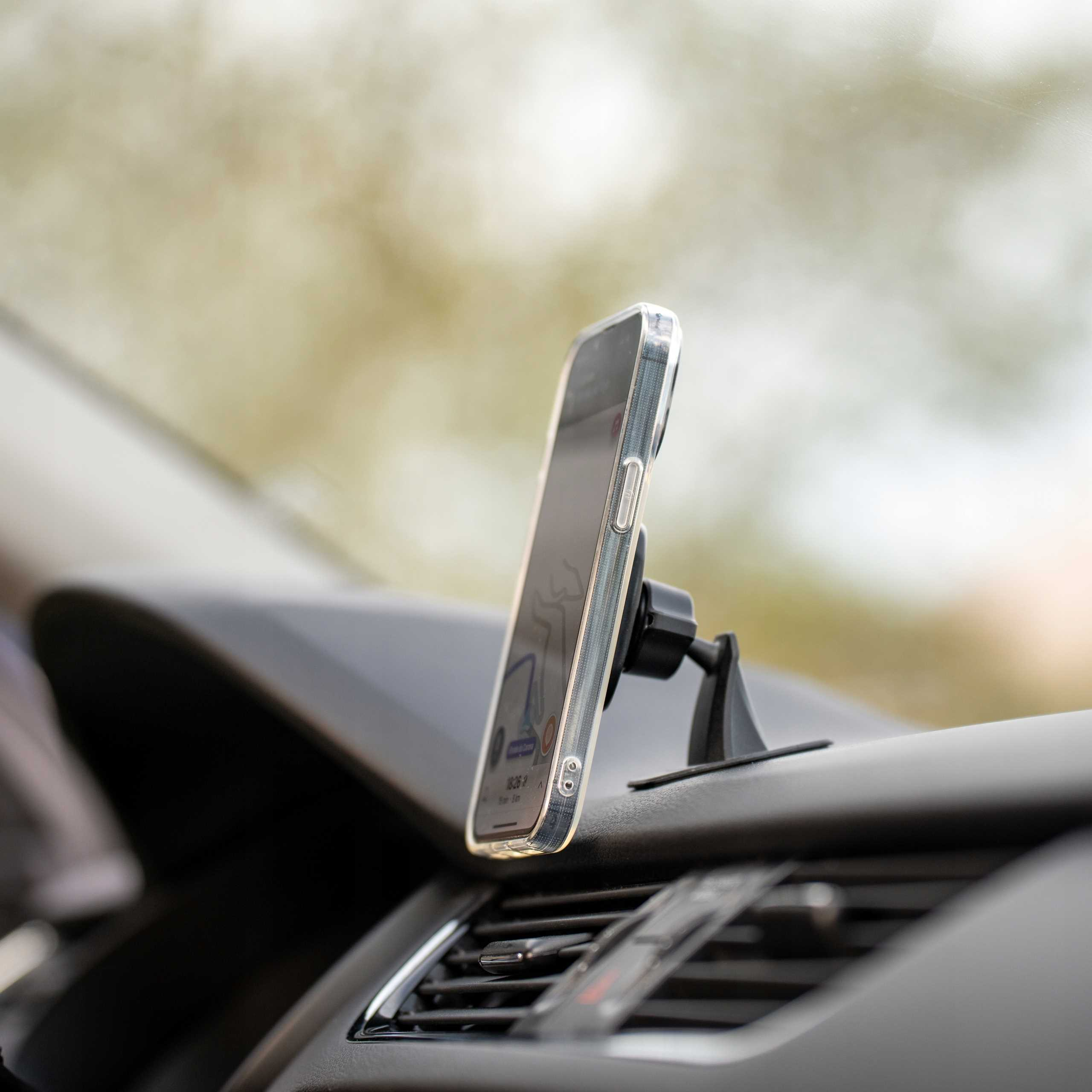 Smartfon w przezroczystym etui zamontowany na desce rozdzielczej samochodu. Na ekranie aplikacja nawigacyjna.