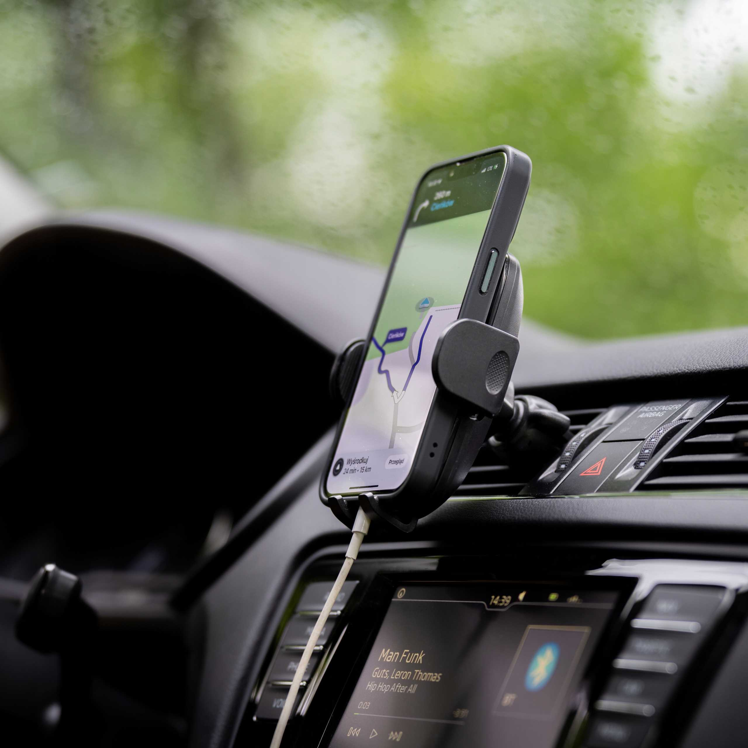 Telefon z aplikacją nawigacyjną jest zamontowany w samochodzie. Ekran pokazuje mapę. Deska rozdzielcza jest czarna.