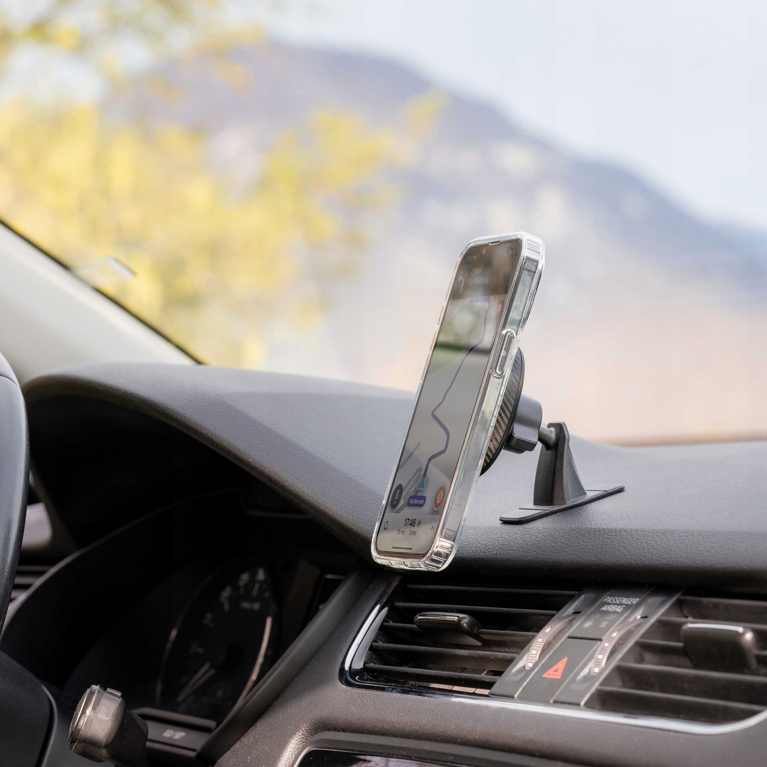 Telefon z nawigacją na desce rozdzielczej samochodu. Telefon jest zamontowany na uchwycie. Tło jest rozmyte.