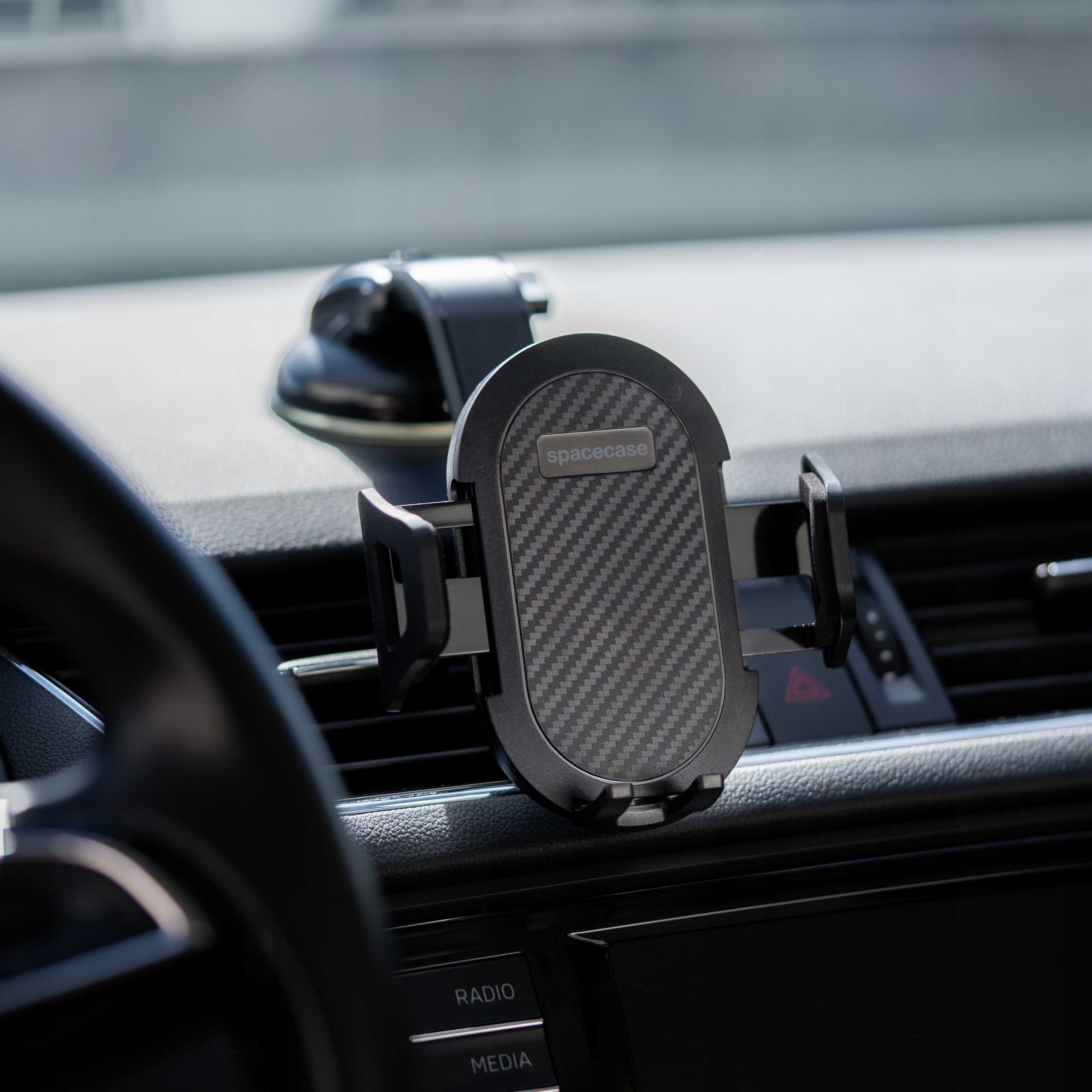 Uchwyt samochodowy na telefon z włókna węglowego. Widoczna deska rozdzielcza, kierownica i detale.