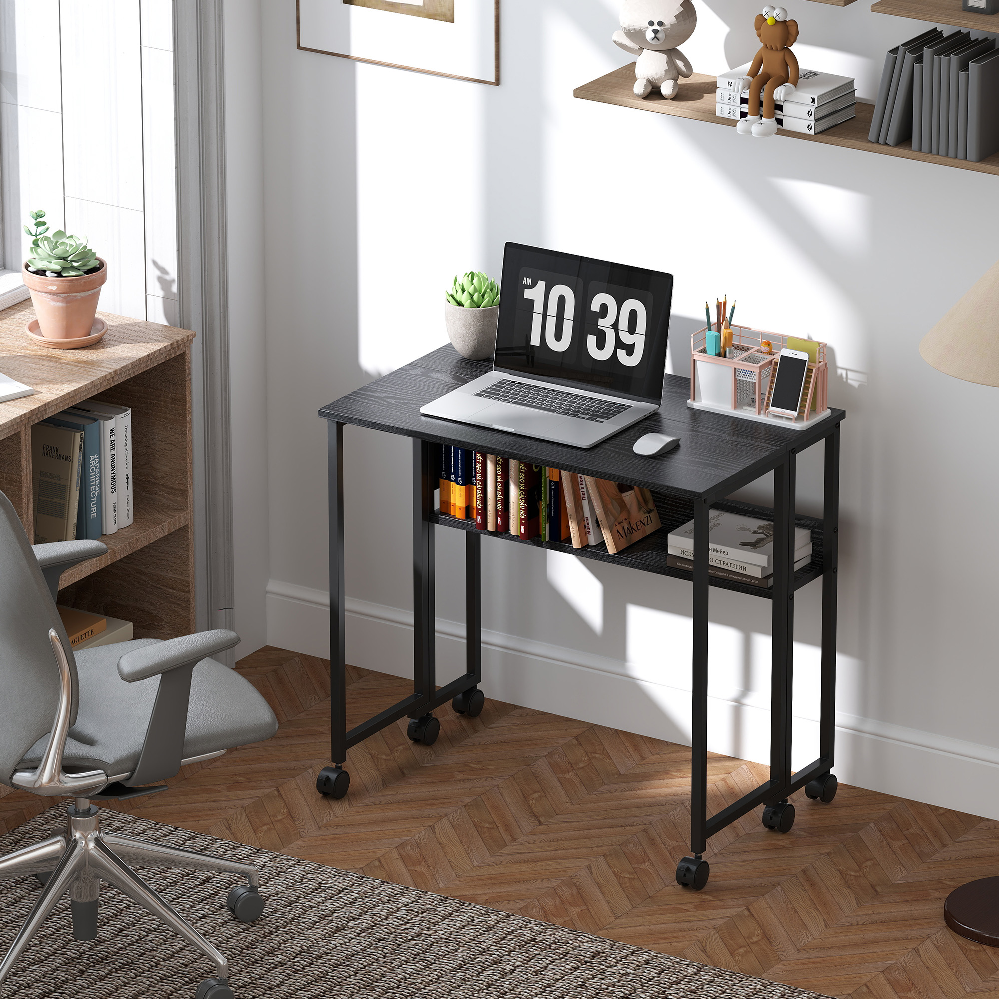 Una scrivania con laptop, libri e forniture per ufficio. Sono visibili anche una finestra e una sedia. L'ora sul laptop è 10:39.