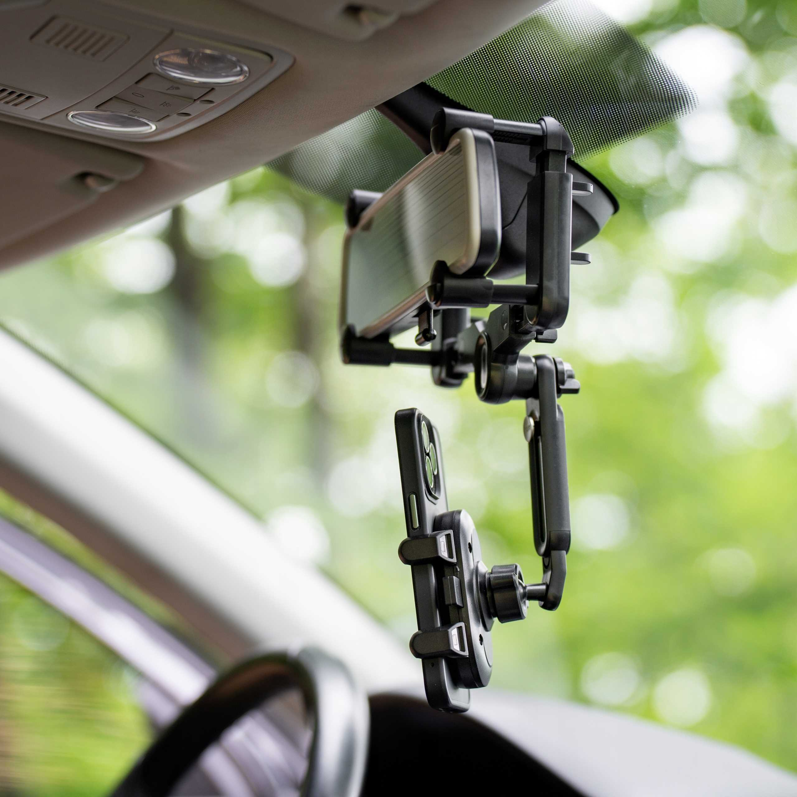 Telefon jest zamontowany na przedniej szybie samochodu za pomocą czarnego uchwytu. Tło to zielone, rozmyte drzewo.