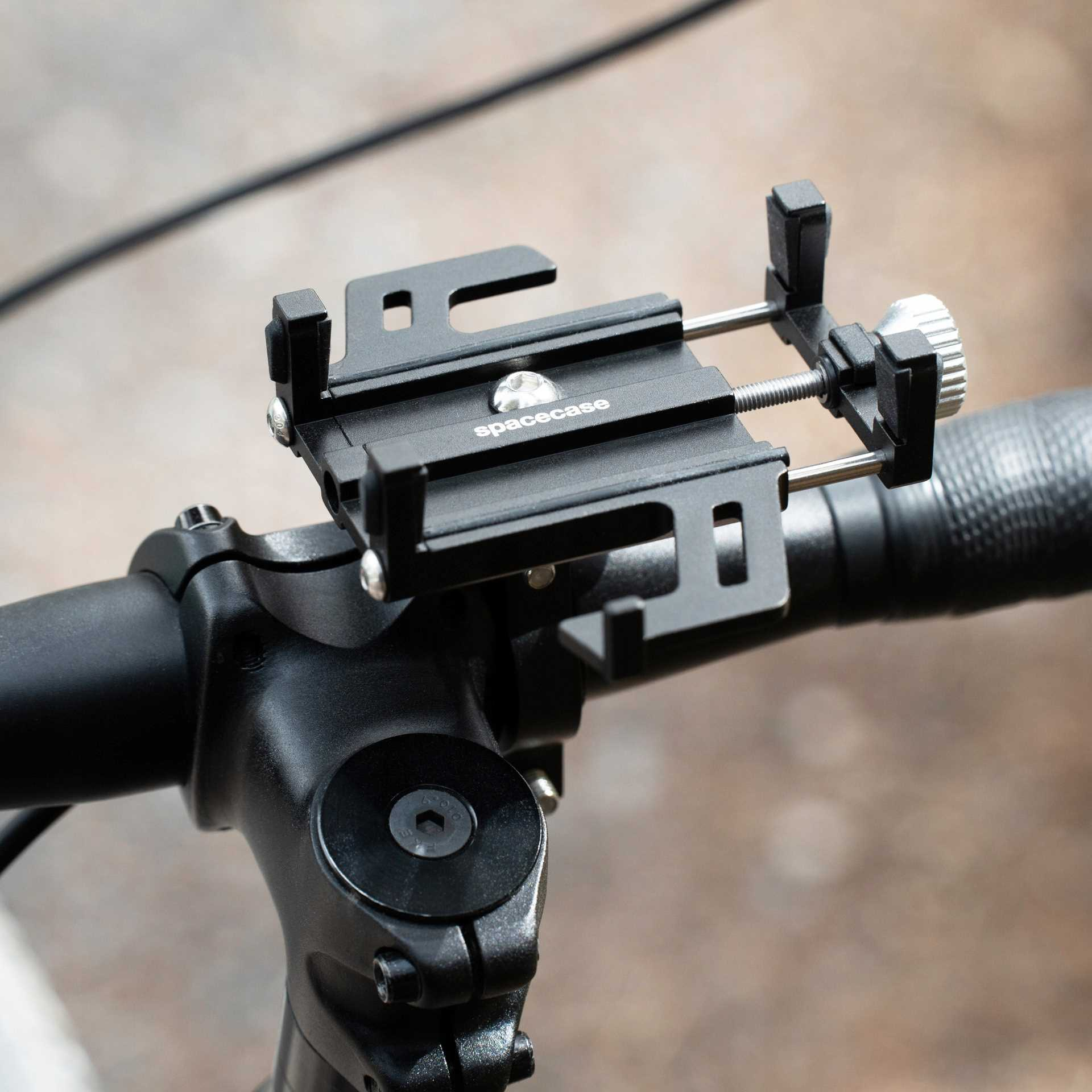 Czarny uchwyt na telefon do roweru na kierownicy, marki 'spacecase'. Zawiera śrubę regulacyjną i ramiona zaciskowe.