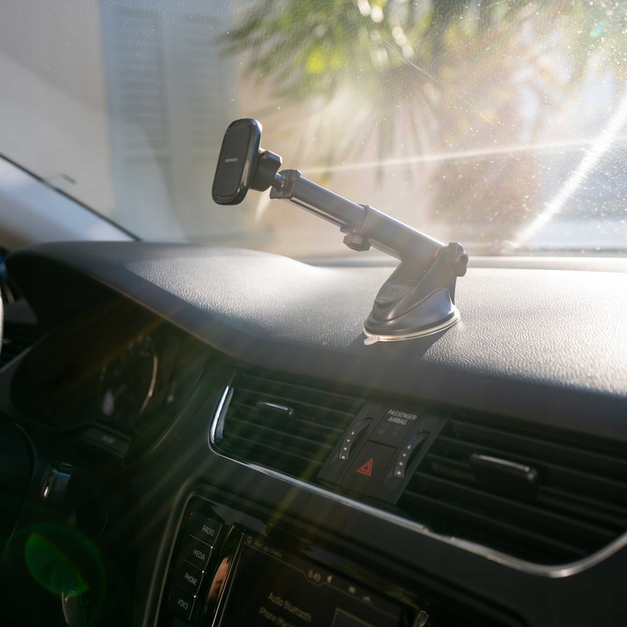 Wnętrze samochodu z uchwytem na telefon na desce rozdzielczej. Słońce przez przednią szybę.