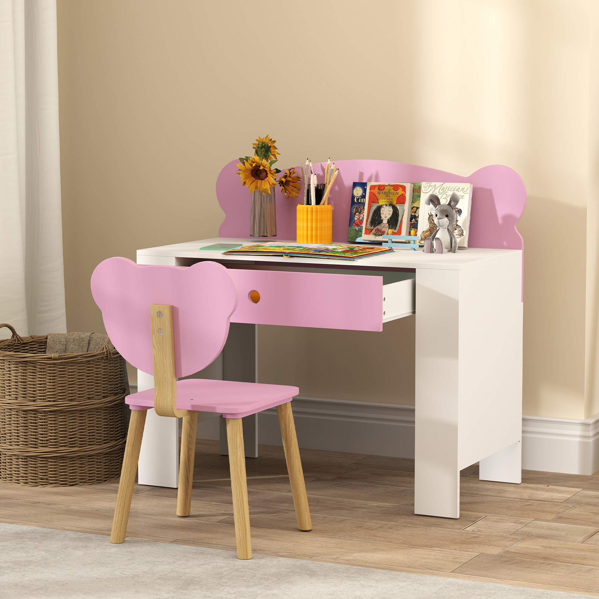 Un set scrivania e sedia rosa a forma di orso con libri, matite, girasoli e un peluche sulla scrivania.