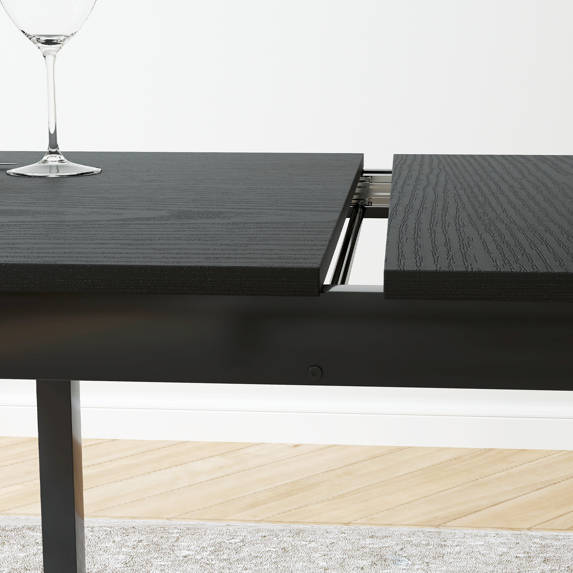 Tavolo in legno nero con sezione aperta e bicchiere da vino. Pavimento in legno chiaro e muro bianco.
