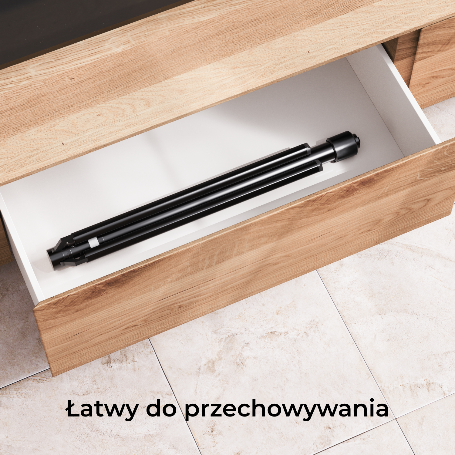 Czarny, złożony statyw jest przechowywany w otwartej drewnianej szufladzie. Szuflada jest częścią jasnej drewnianej szafki, na kafelkowej podłodze.