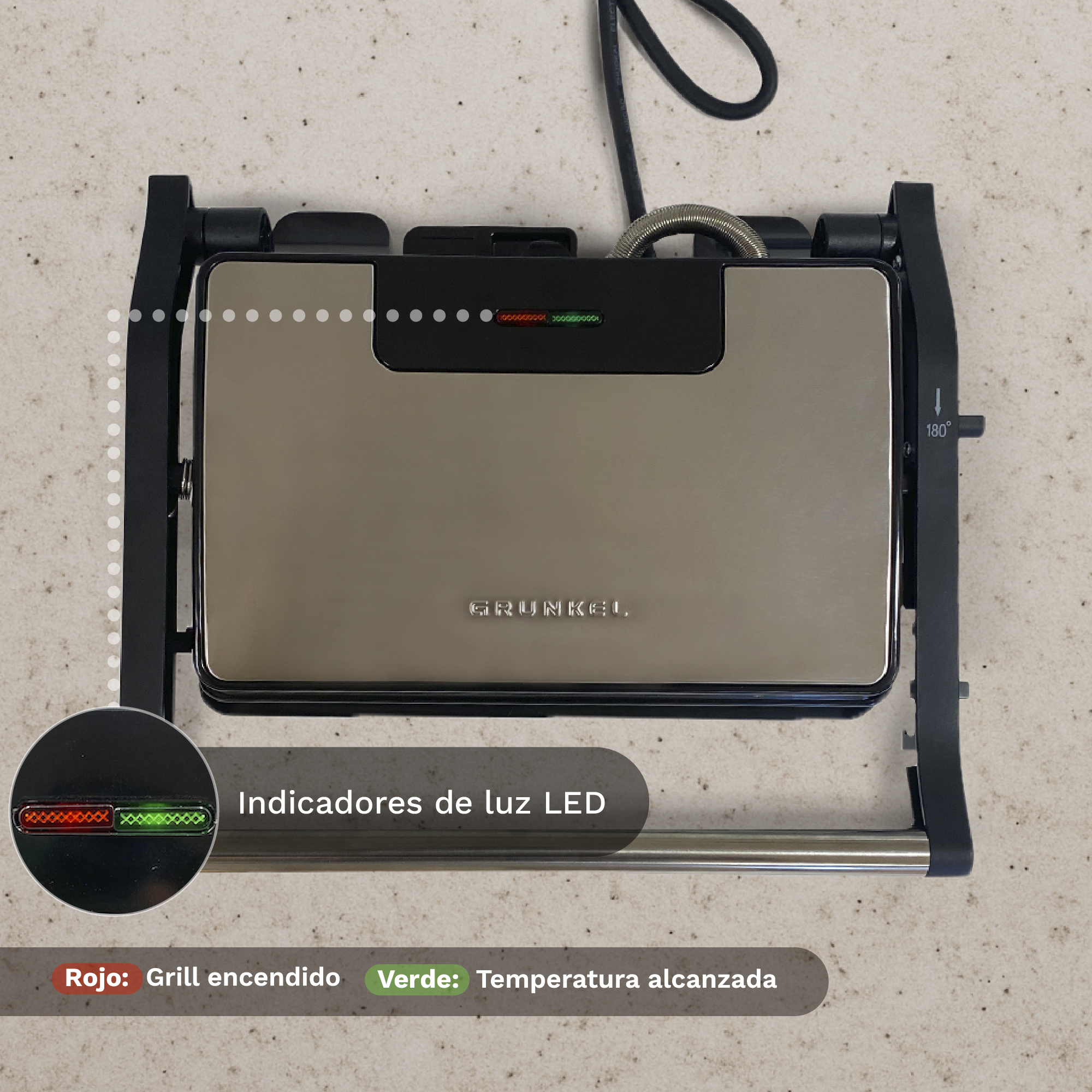 Una griglia Grunkel argentata su una superficie beige. Ha un indicatore LED rosso/verde e una maniglia nera. Il cavo è nero.