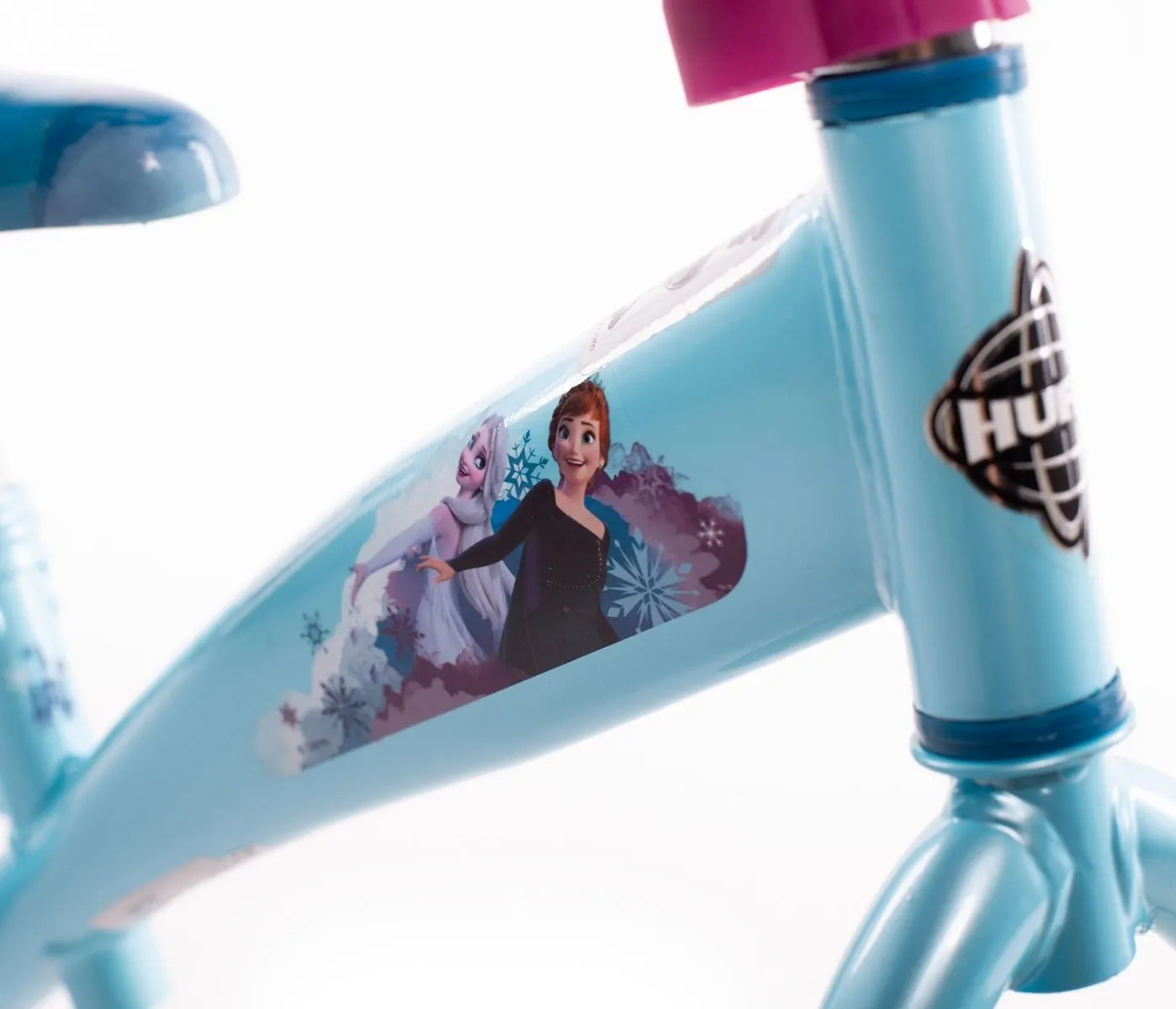 Zbliżenie jasnoniebieskiej ramy roweru. Zawiera postacie z Krainy Lodu i czarne logo. Siodło i kierownica są różowe i niebieskie.