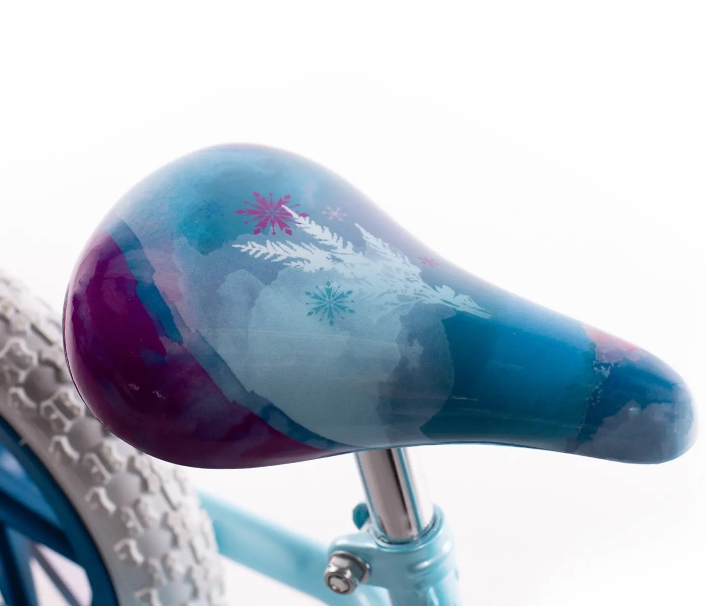 Zbliżenie siodełka rowerowego z motywem Krainy Lodu. Siedzisko jest niebieskie z fioletowymi akcentami i wzorami płatków śniegu. Widoczna jest część opony.
