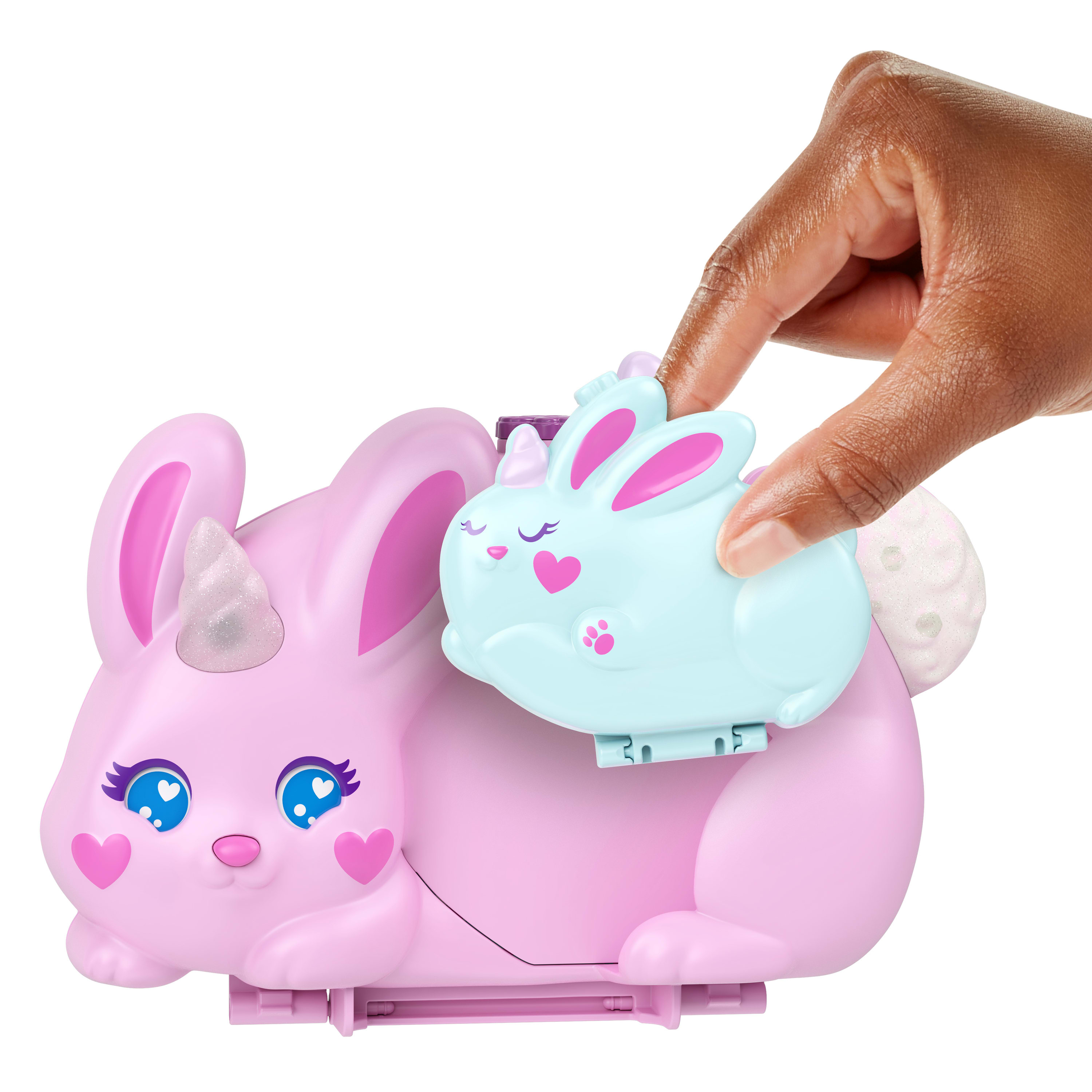 Eine Hand hält einen hellblauen Spielzeug-Hasen. Der Spielzeug-Hase sitzt auf einem rosa Hasen. Das Spielzeug hat Herzen und ein Einhornhorn.