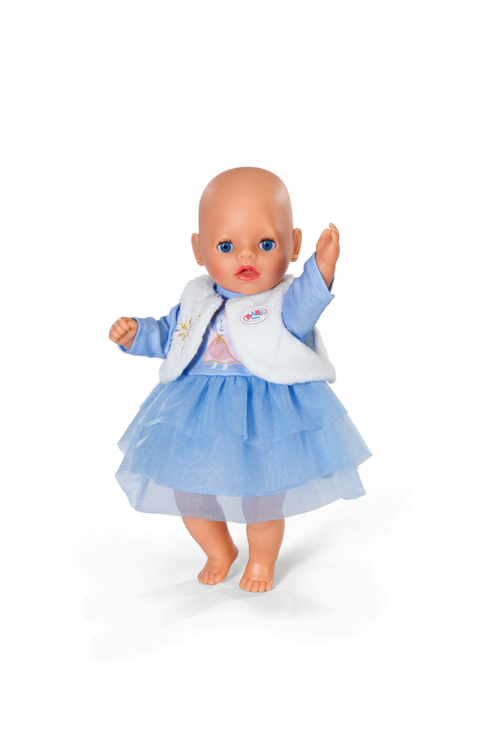 Lalka z niebieskimi oczami, w niebieskiej sukience i białej kamizelce. Lalka stoi na białym tle i podnosi prawą rękę.