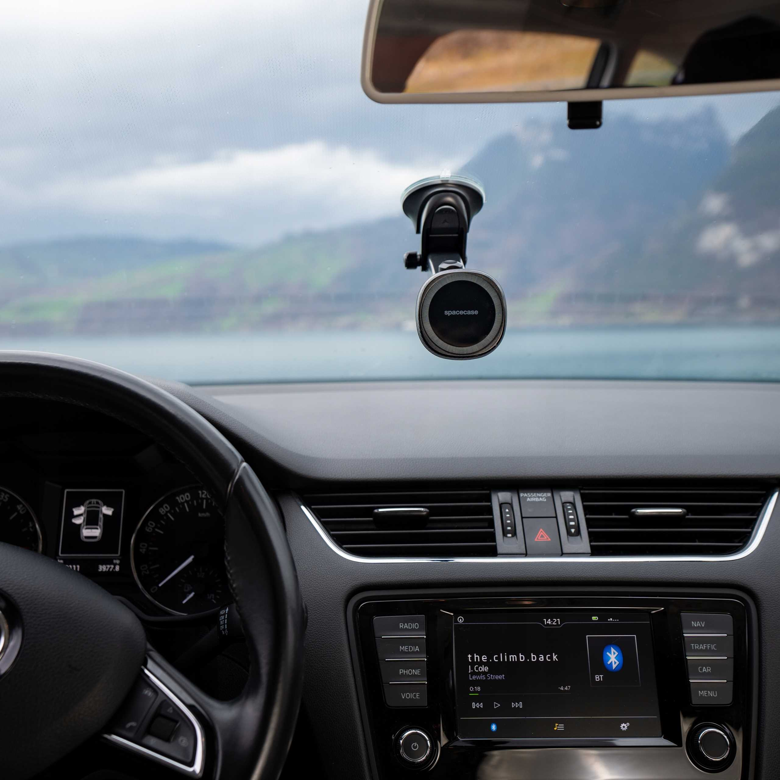 Widok wnętrza samochodu. Kierownica, deska rozdzielcza, uchwyt na telefon na przedniej szybie, góry.