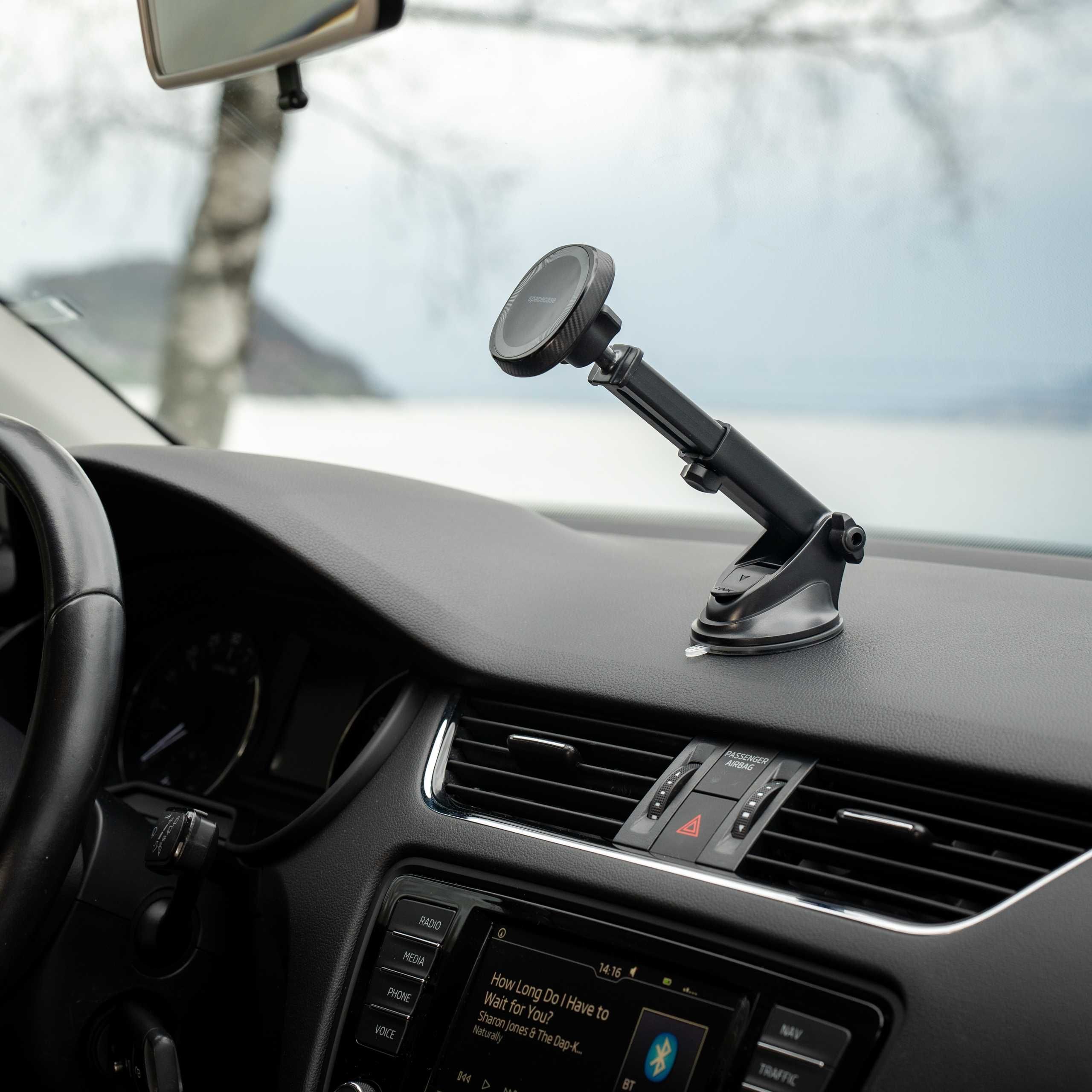 Wnętrze samochodu. Uchwyt na telefon na desce rozdzielczej. Kierownica po lewej stronie. Ekran radia i muzyki pośrodku.