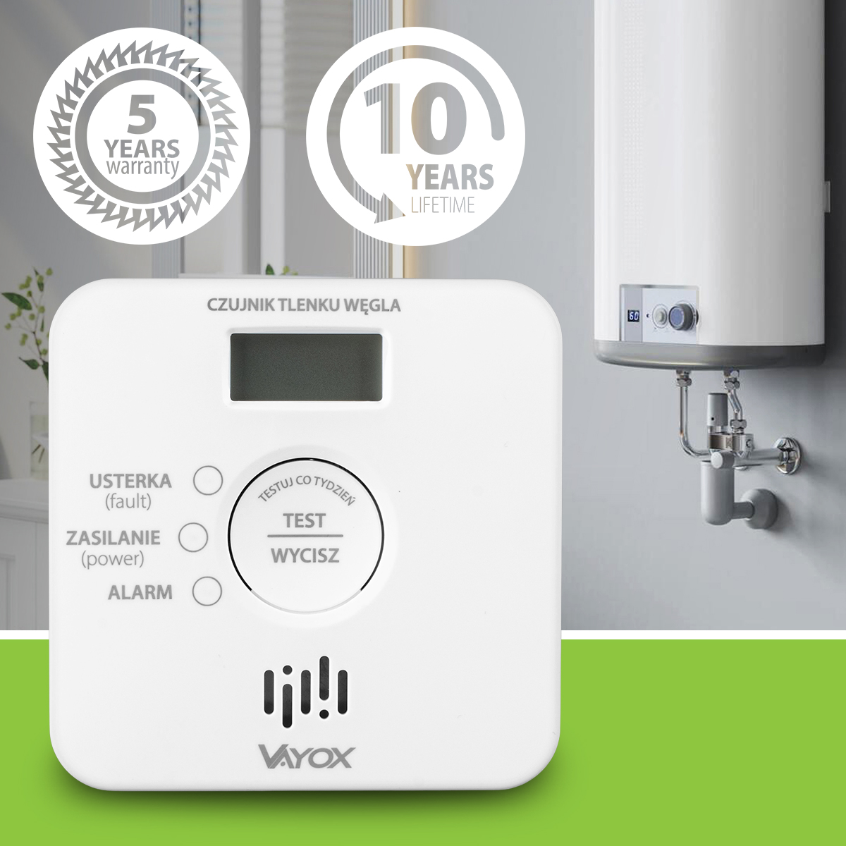 Biały czujnik tlenku węgla z ekranem, ikonami gwarancji i podgrzewaczem wody na ścianie.