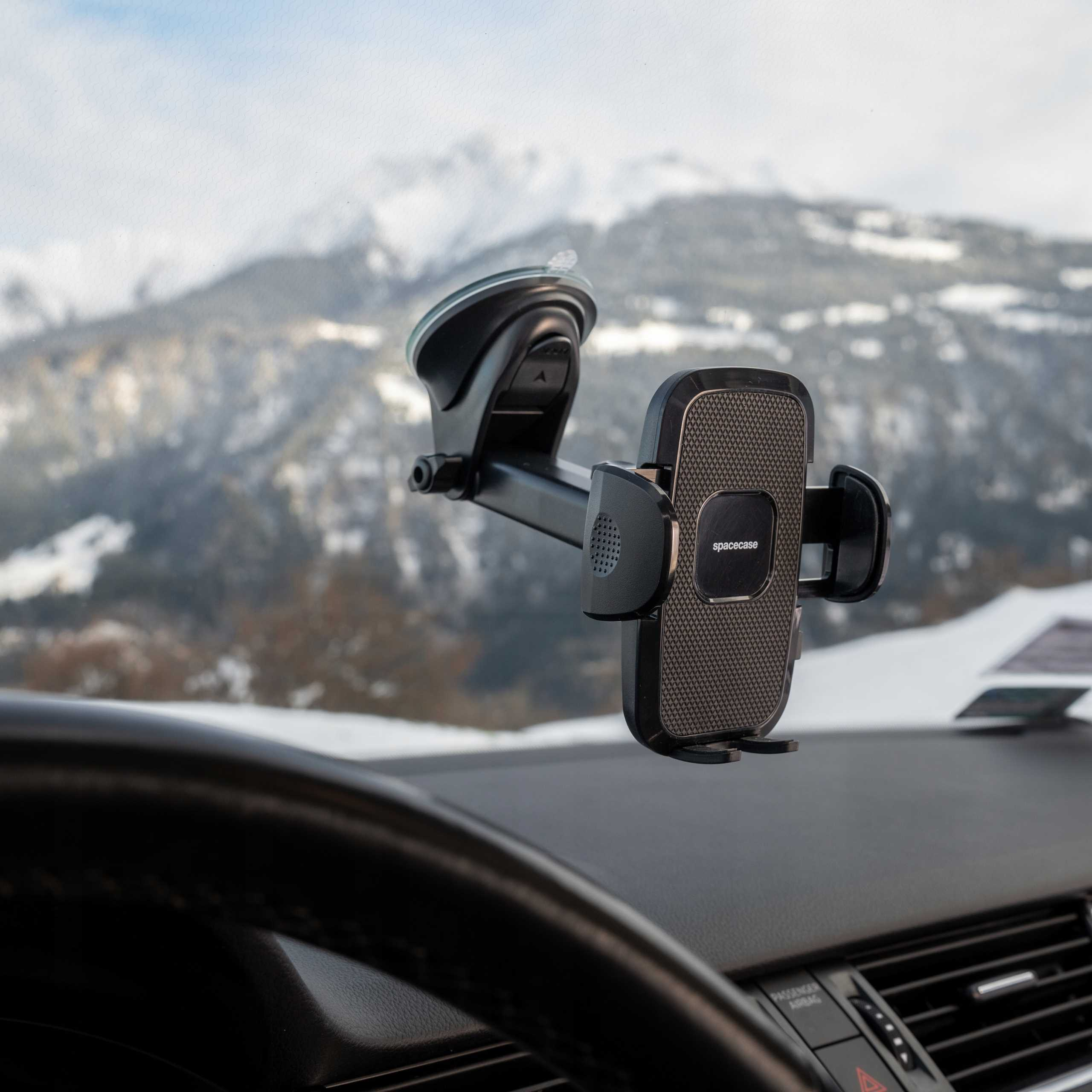 Uchwyt do telefonu samochodowego jest zamontowany na przedniej szybie. Łańcuch górski jest widoczny przez przednią szybę ze śniegiem.