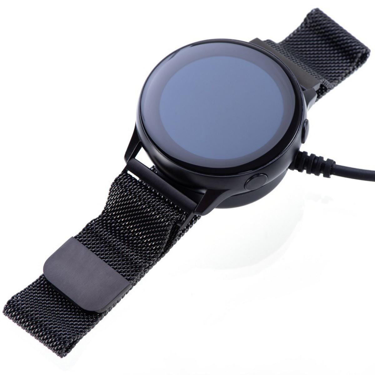 Uno smartwatch nero con cinturino magnetico su una superficie bianca. L'orologio è collegato a un caricabatterie.