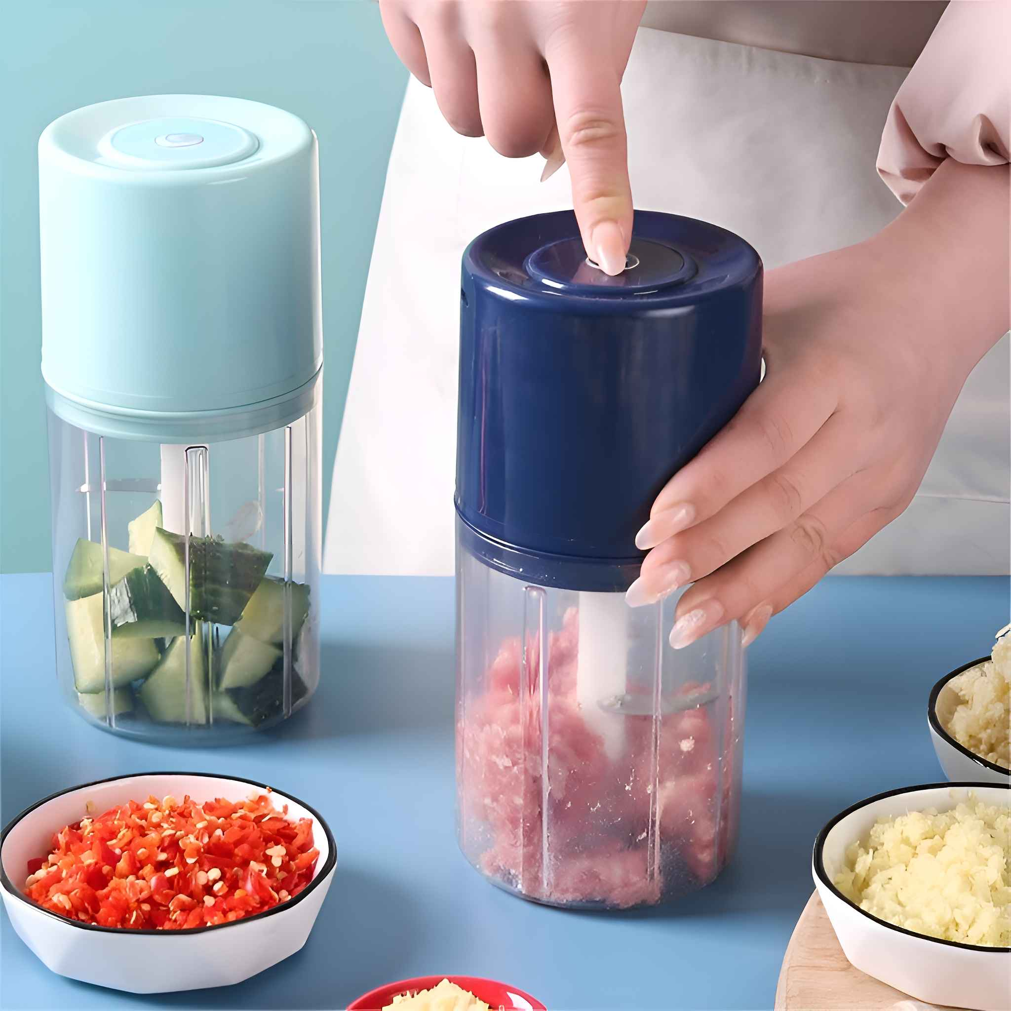 Eine Person benutzt einen blauen Foodprozessor. Gehacktes Gemüse befindet sich im Prozessor und in Schalen. Eine Hand drückt den Knopf.