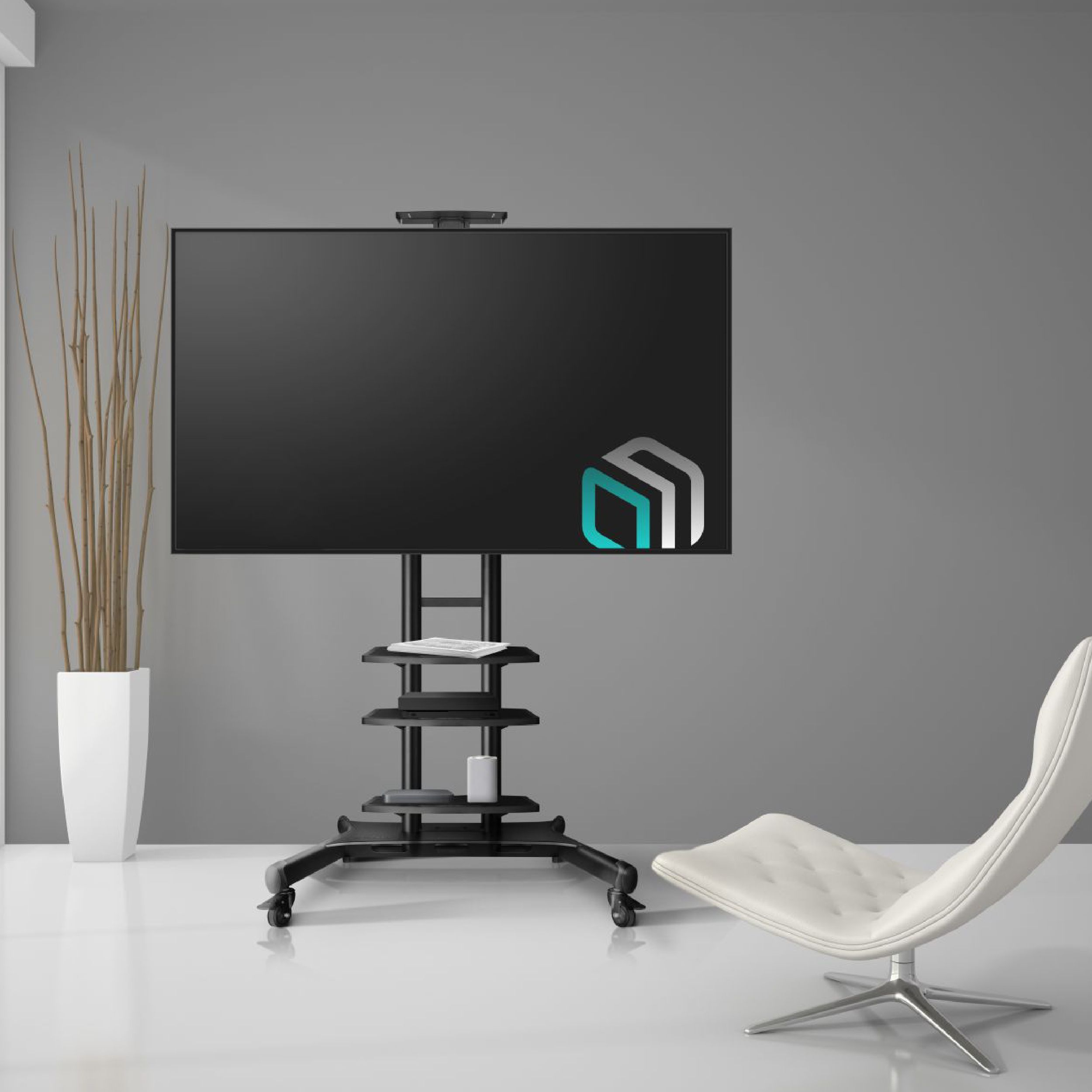 Ein großer schwarzer Fernseher auf einem rollenden Ständer. Ein weißer Stuhl und eine Pflanze befinden sich rechts und links. Graue Wand und weißer Boden.