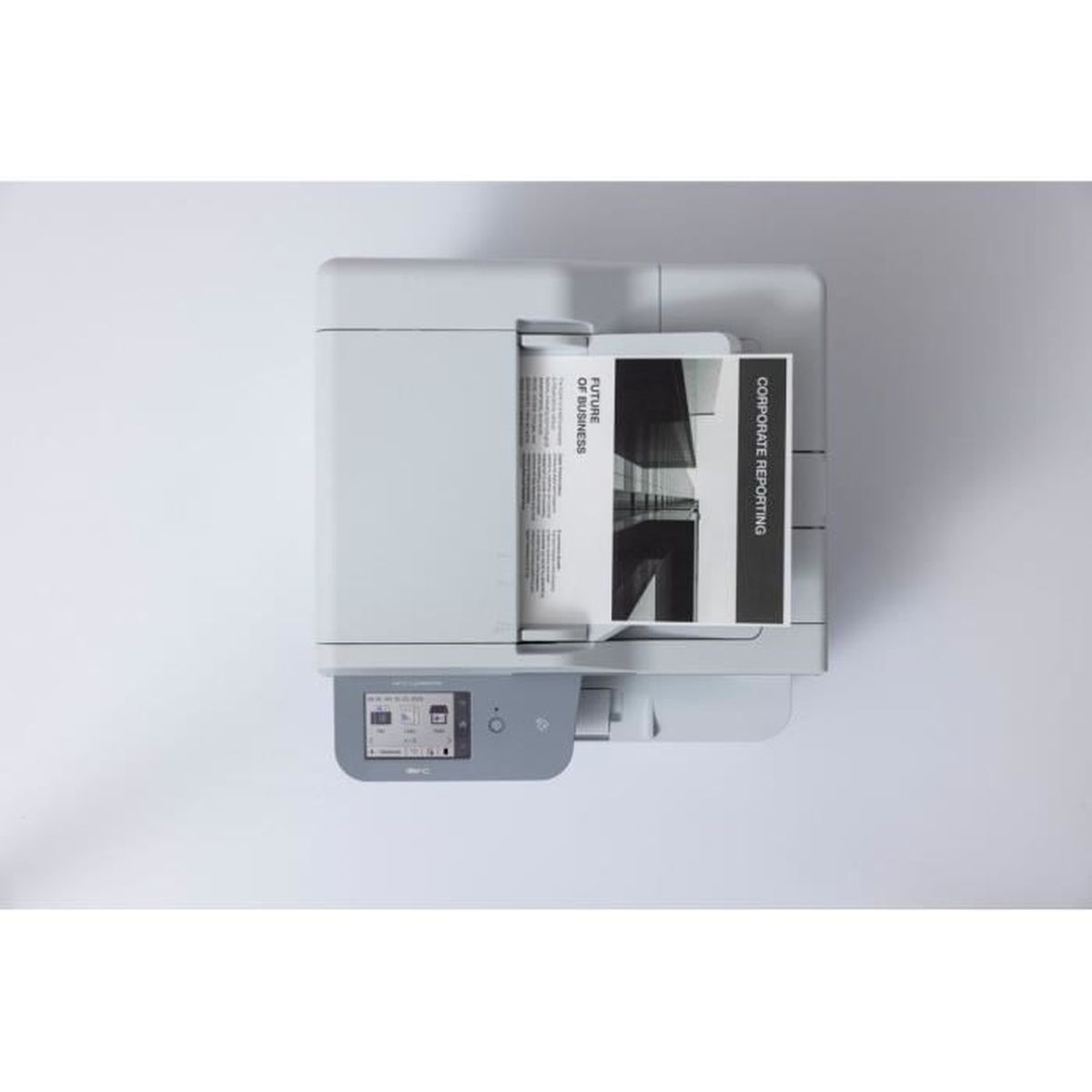 Drukarka z kartką papieru z napisem 'Future of Business' i 'Corporate Reporting' stoi na białej powierzchni, widok z góry.