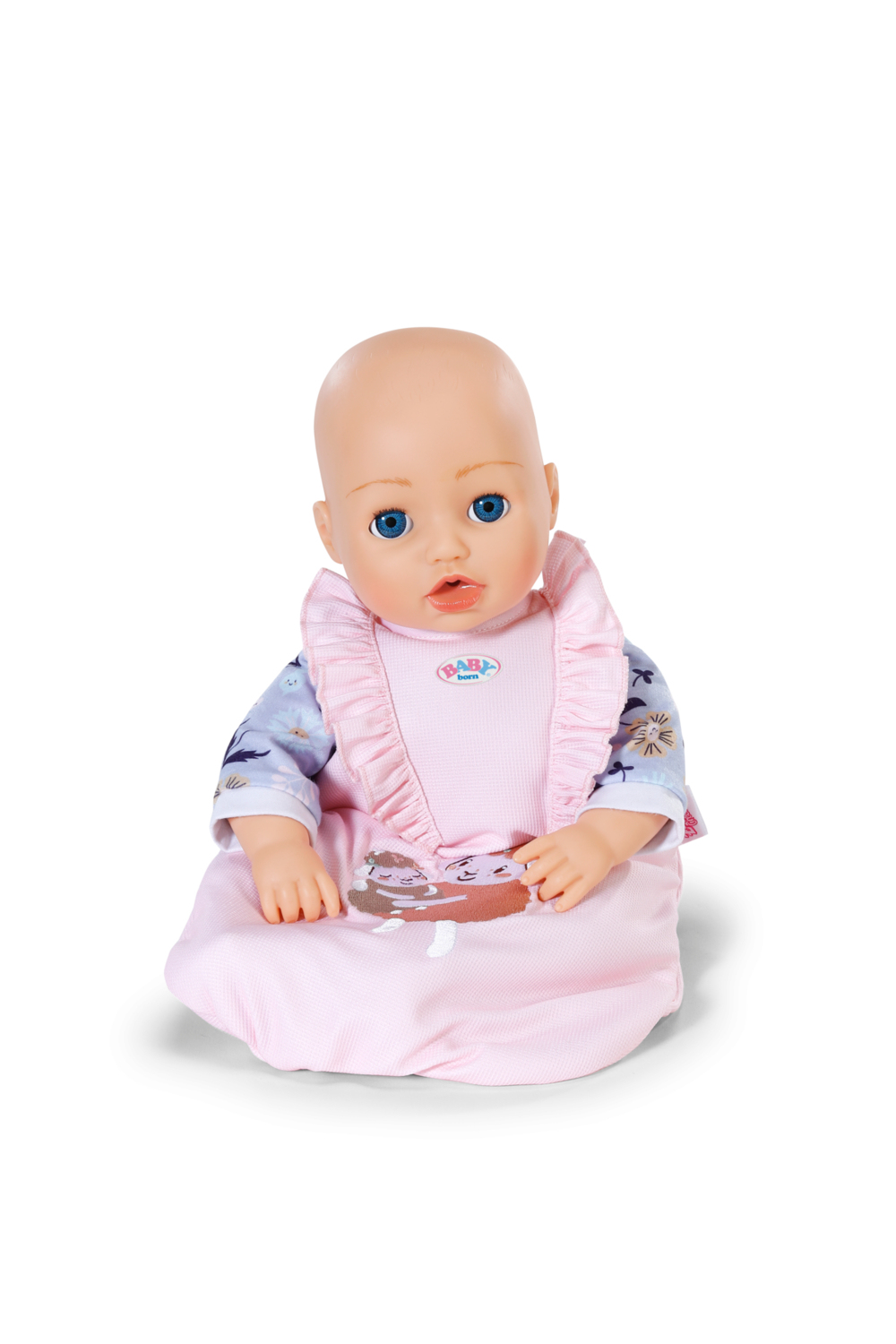 Lalka dla dziecka z niebieskimi oczami w różowym śliniaczku i piżamie. Lalka siedzi, tło jest białe.