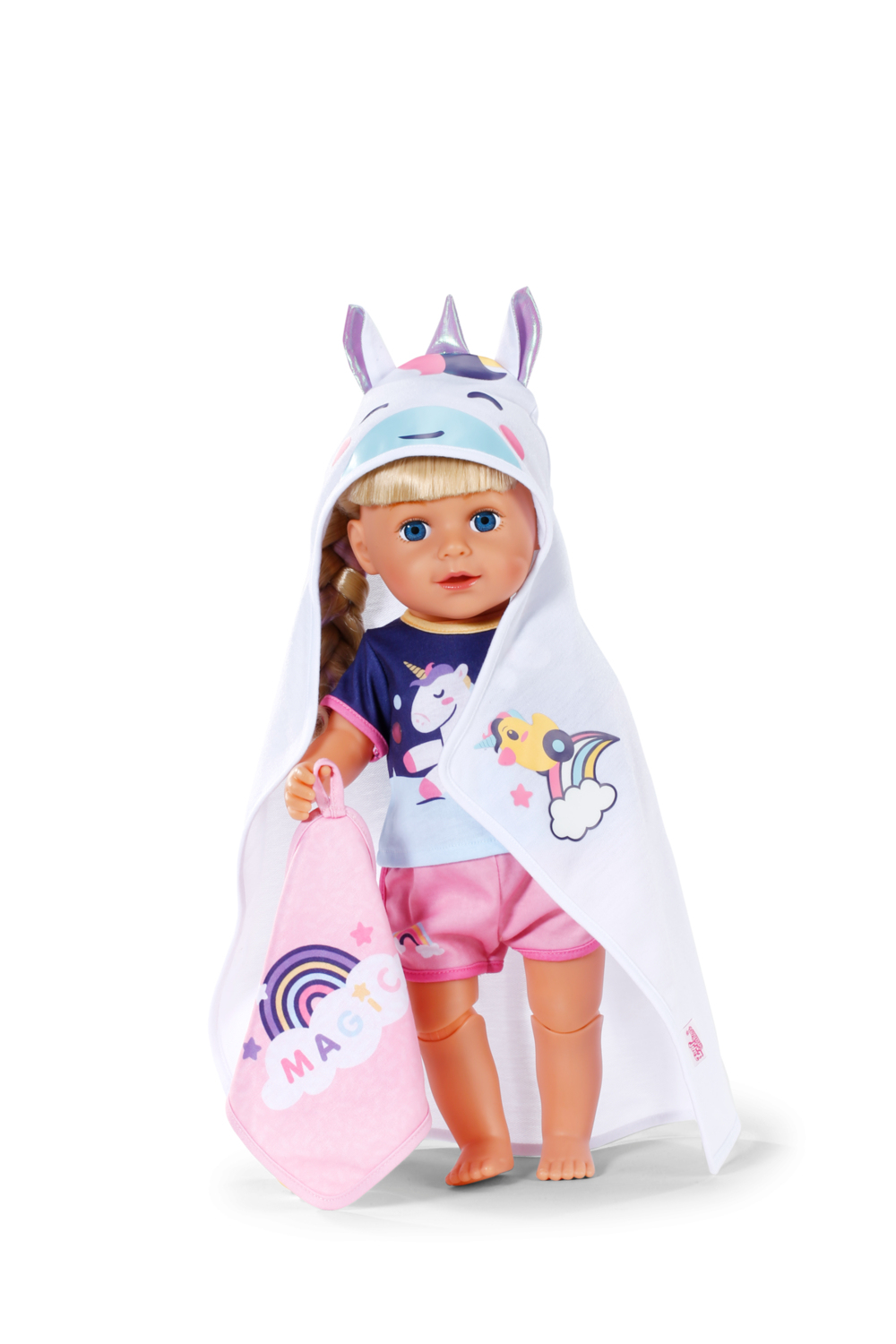 Lalka w kapturze i ręczniku jednorożca. Ma blond włosy i niebieskie oczy. Trzyma różowy ręcznik z tęczą.