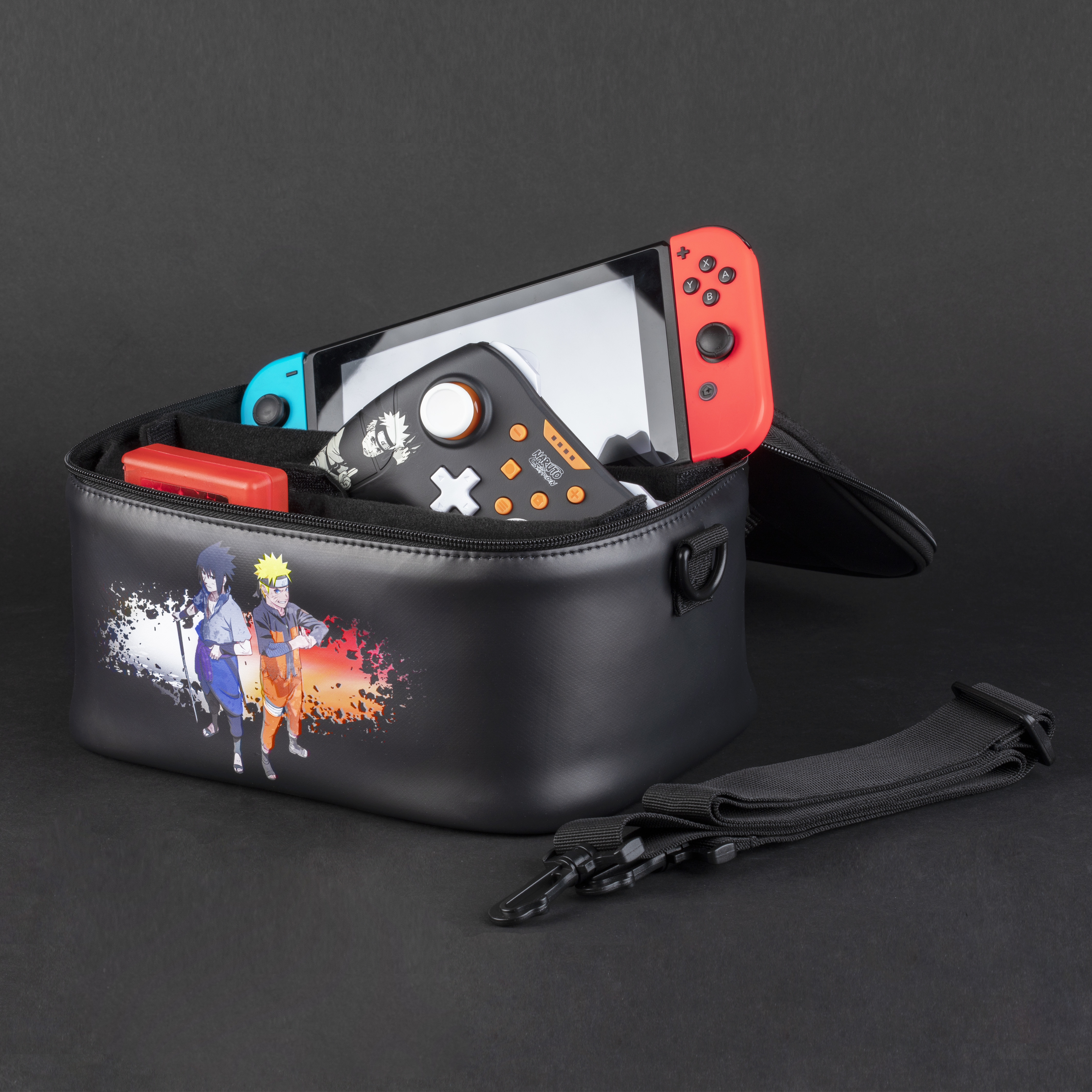 Czarna torba z postaciami z Naruto. W środku znajduje się Nintendo Switch, kontroler i kartridż do gier. Czarne tło.