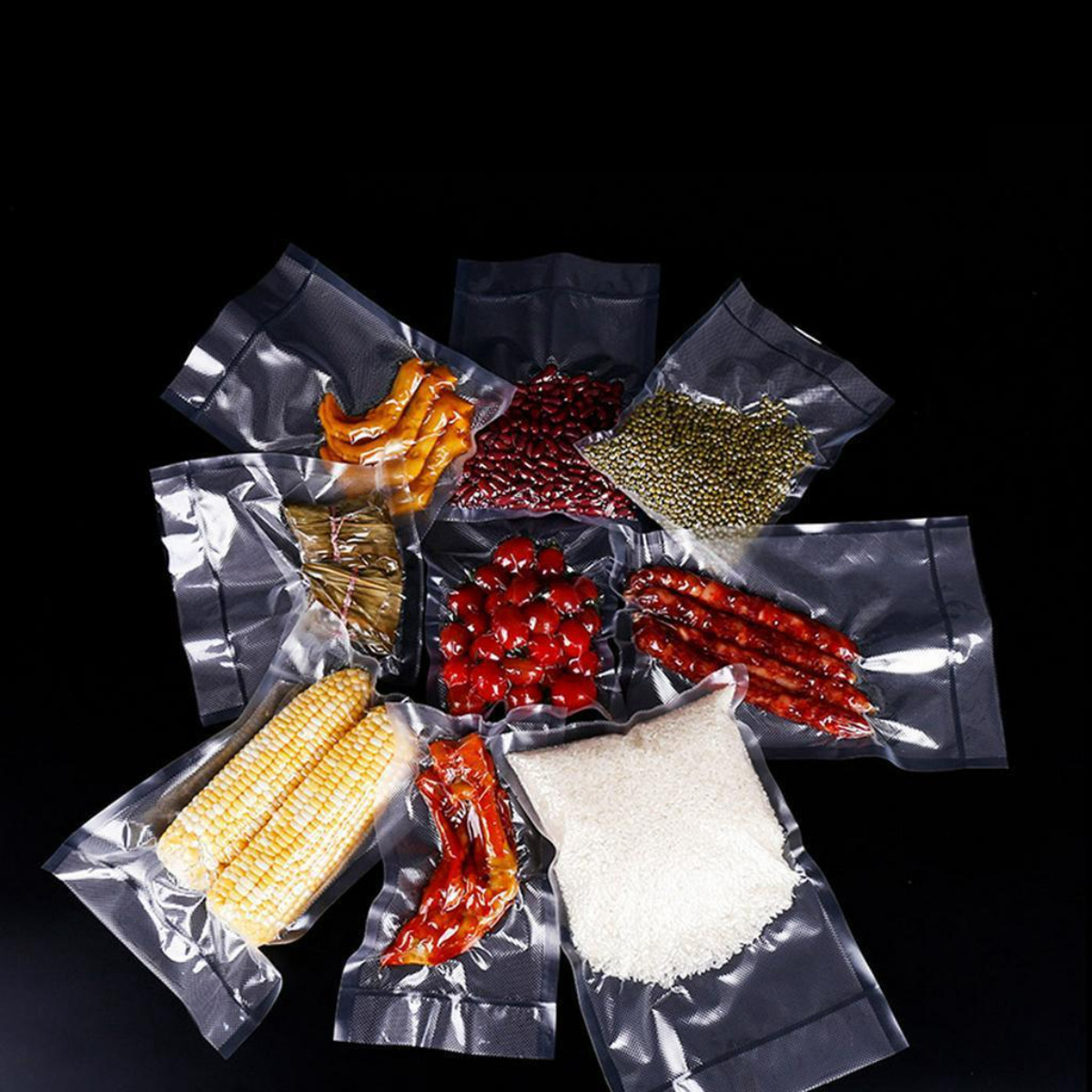 Varios alimentos en bolsas selladas al vacío: maíz, frijoles, arroz, tomates, salchichas y otros ingredientes sobre un fondo negro.