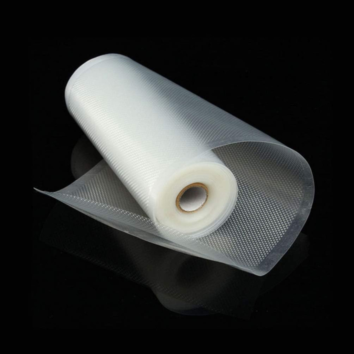 Un rollo de bolsas de plástico transparente para envasar al vacío sobre una superficie negra. Las bolsas están parcialmente desenrolladas, mostrando un patrón punteado.