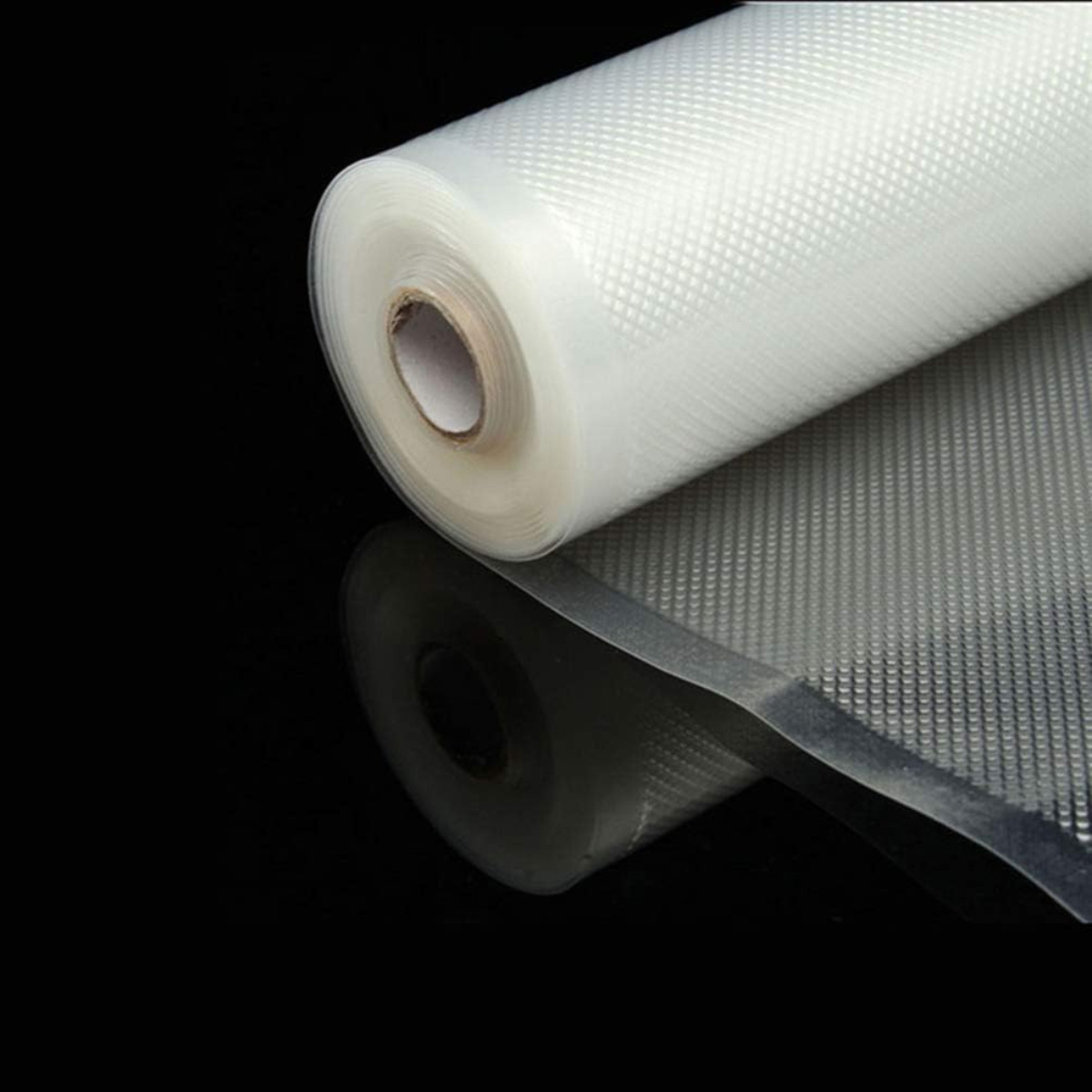 Un rollo de plástico transparente sobre una superficie negra. El envoltorio es texturizado. El reflejo muestra el rollo y una porción del envoltorio.
