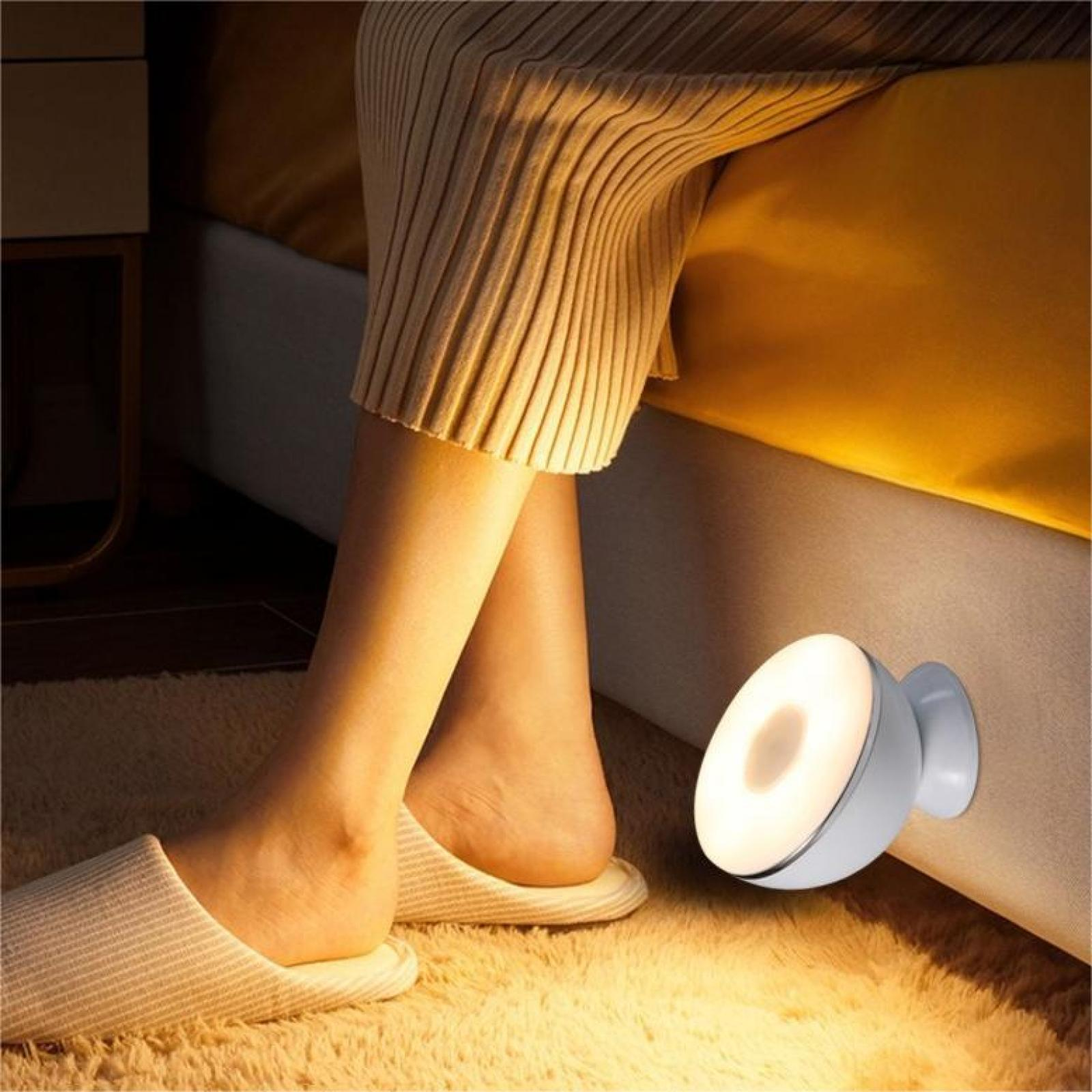 Personenbeine und Füße in der Nähe eines Bettes, mit Pantoffeln. Eine runde, weiße Nachttischlampe leuchtet.