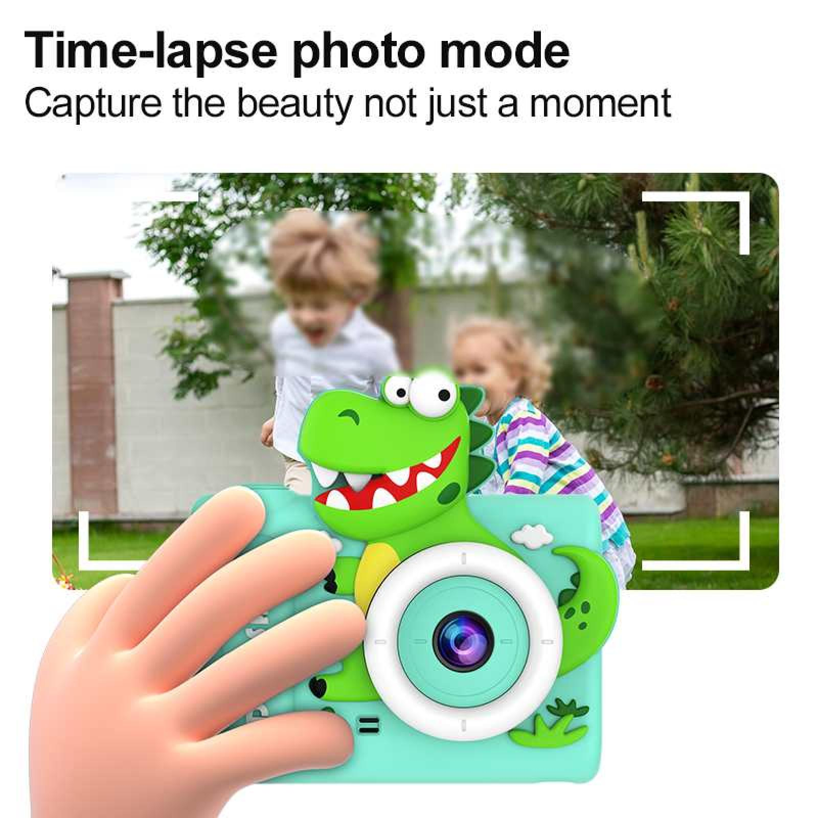 Eine Hand hält eine grüne Kamera in Dinosaurierform. Im Hintergrund sind zwei Kinder. Die Kamera hat ein weißes Objektiv und ein rotes Lächeln.