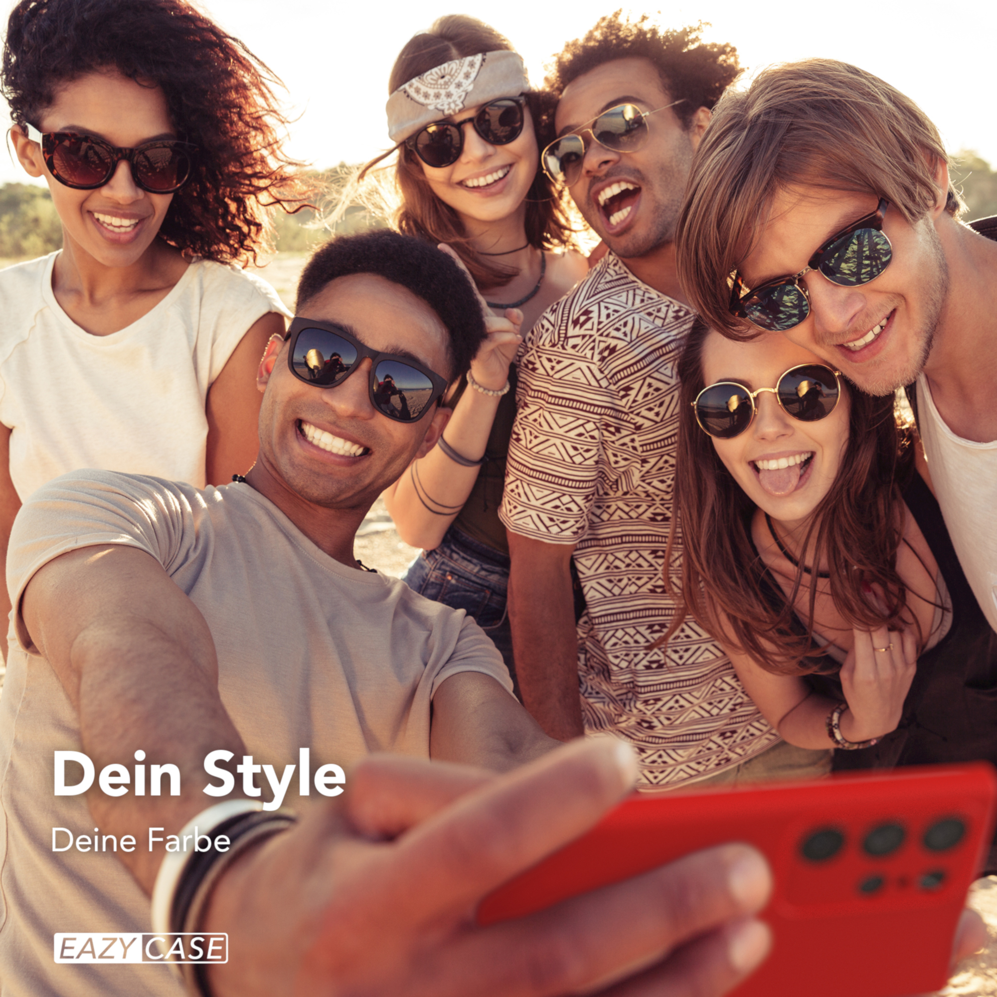 Eine Gruppe von Freunden macht ein Selfie mit einem roten Telefon. Sie lächeln und lachen. Der Hintergrund ist verschwommen.