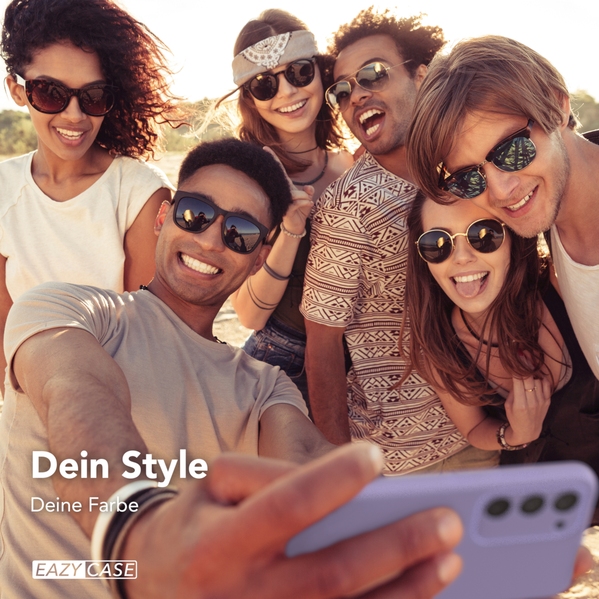 Gruppe von Freunden, die ein Selfie machen und lächeln. Einer hält das Telefon in einer lila Hülle. Strandhintergrund.