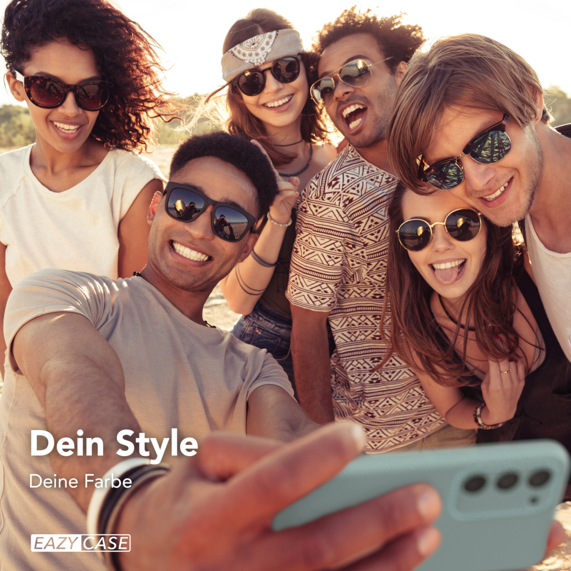 Gruppe von Freunden macht Selfie, alle lächeln. Sonniger Strandhintergrund. Telefon im Vordergrund.