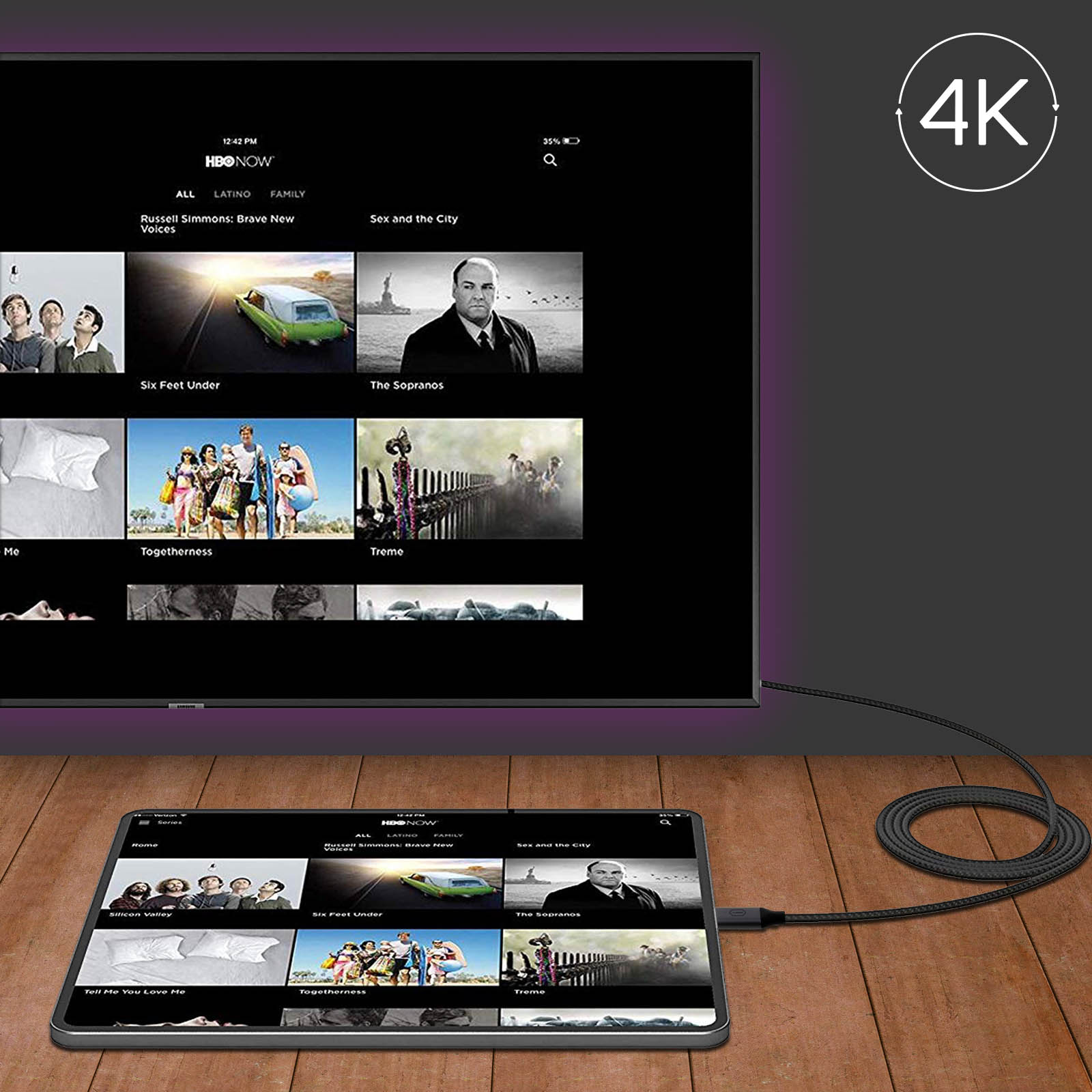Uno schermo TV e un tablet che mostrano l'interfaccia HBO Now. Il tablet è collegato al televisore tramite un cavo, su una superficie in legno.