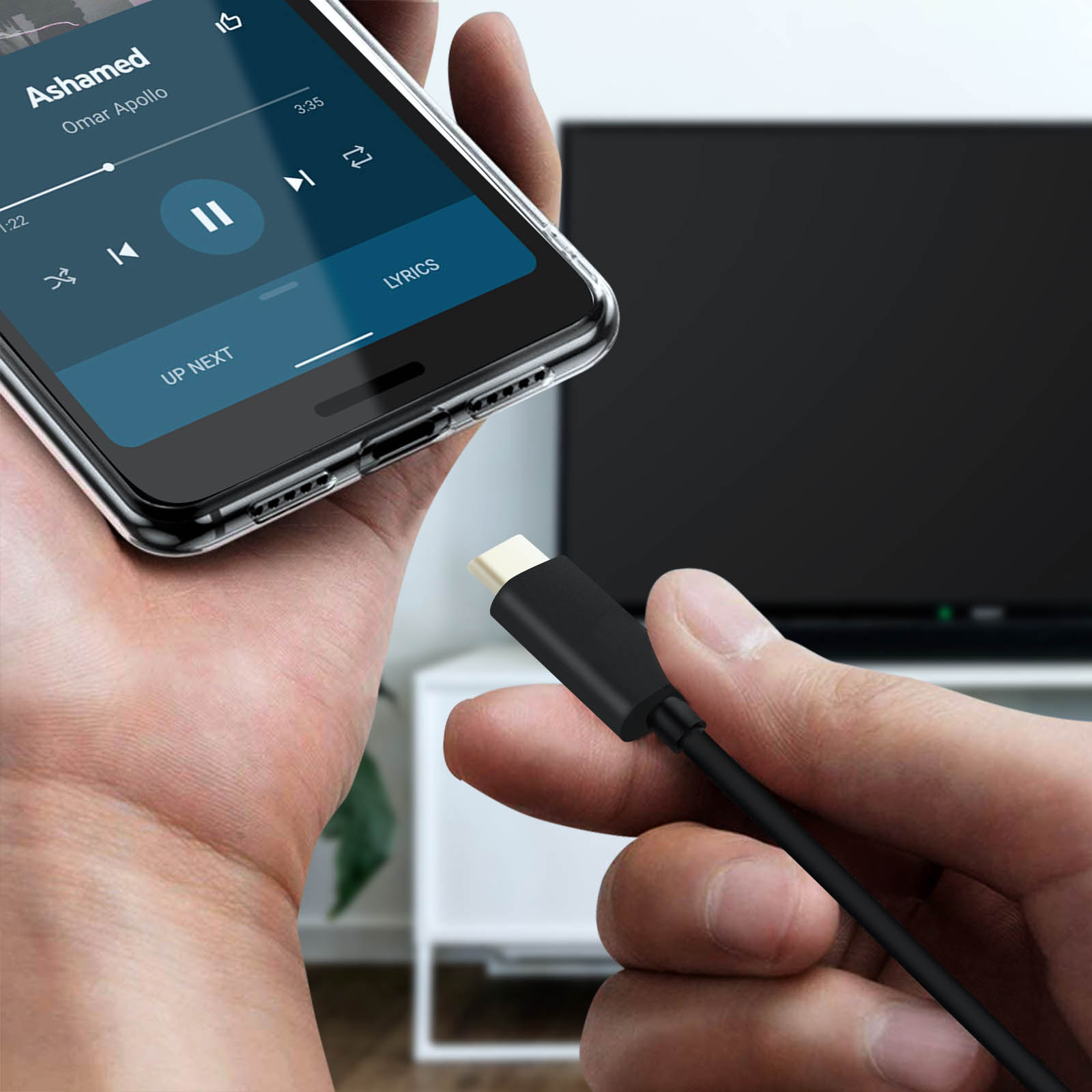 Eine Hand hält ein Telefon, das Musik abspielt, verbunden mit einem schwarzen Kabel. Im Hintergrund ein Fernseher.