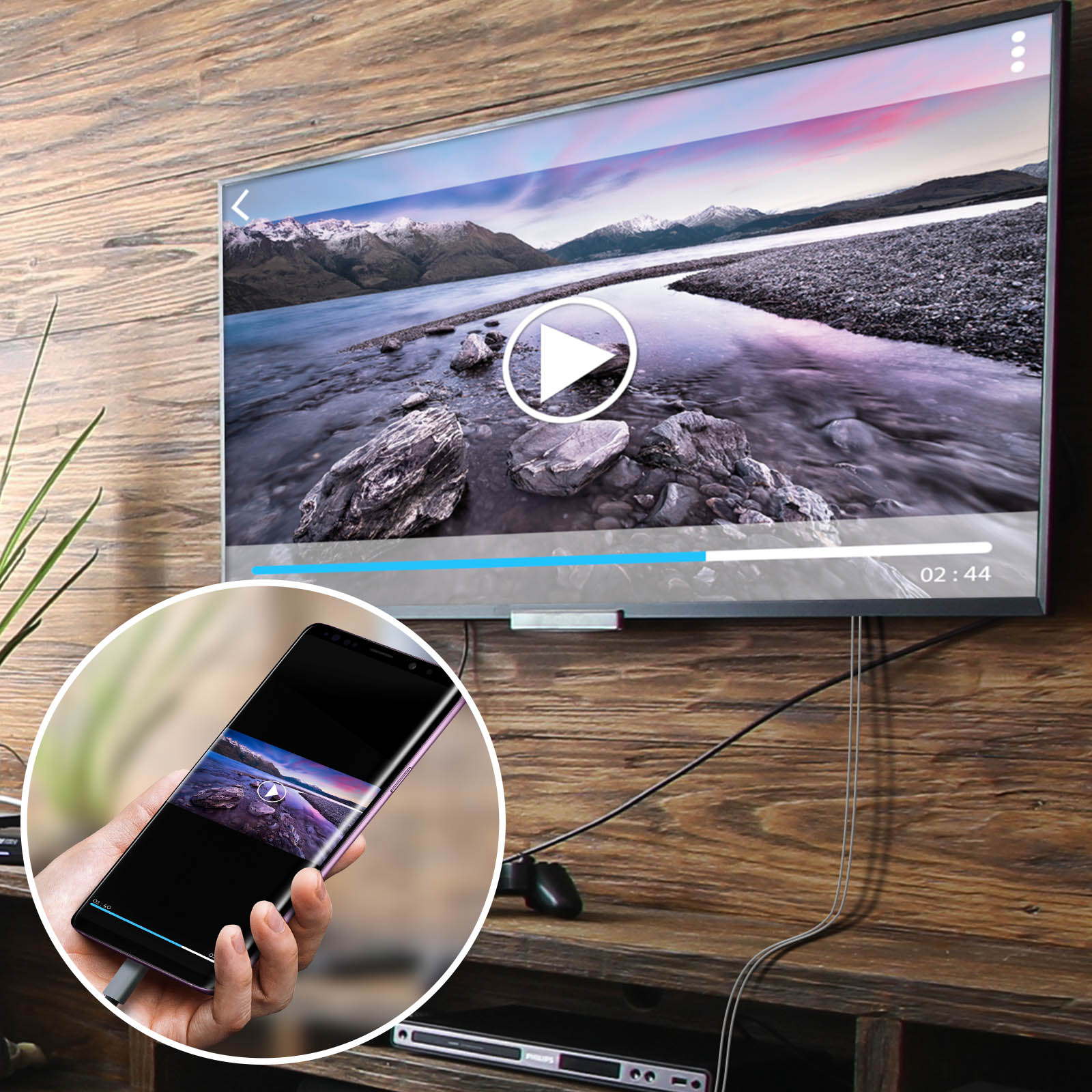 La TV mostra un video di un lago e montagne. Un telefono che rispecchia il video è in mano a qualcuno. Cavi e lettore multimediale sono visibili.