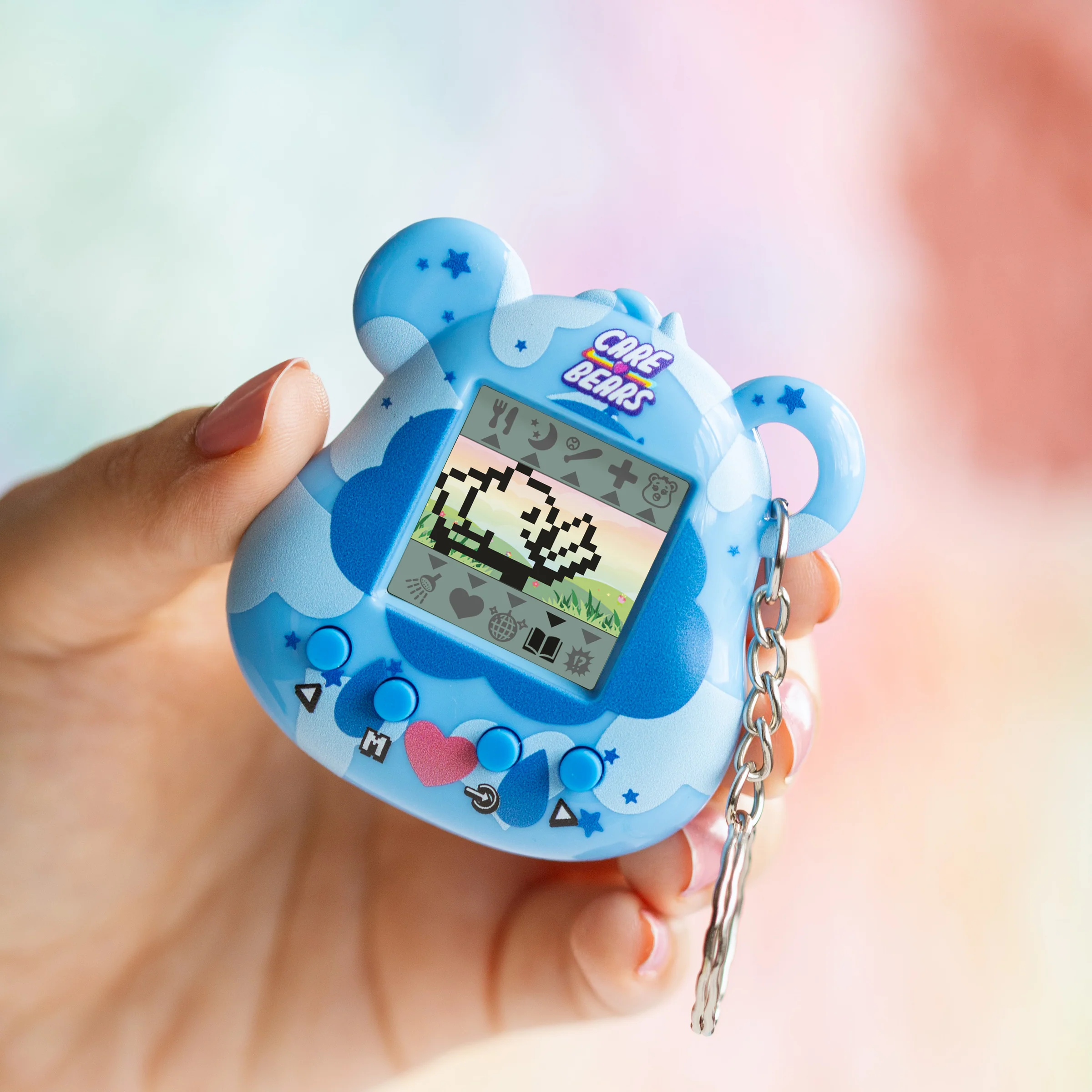 Een blauw Care Bears-speelgoed dat wordt vastgehouden door een hand met roze nagels. Het heeft een scherm met een gepixeld Care Bear.
