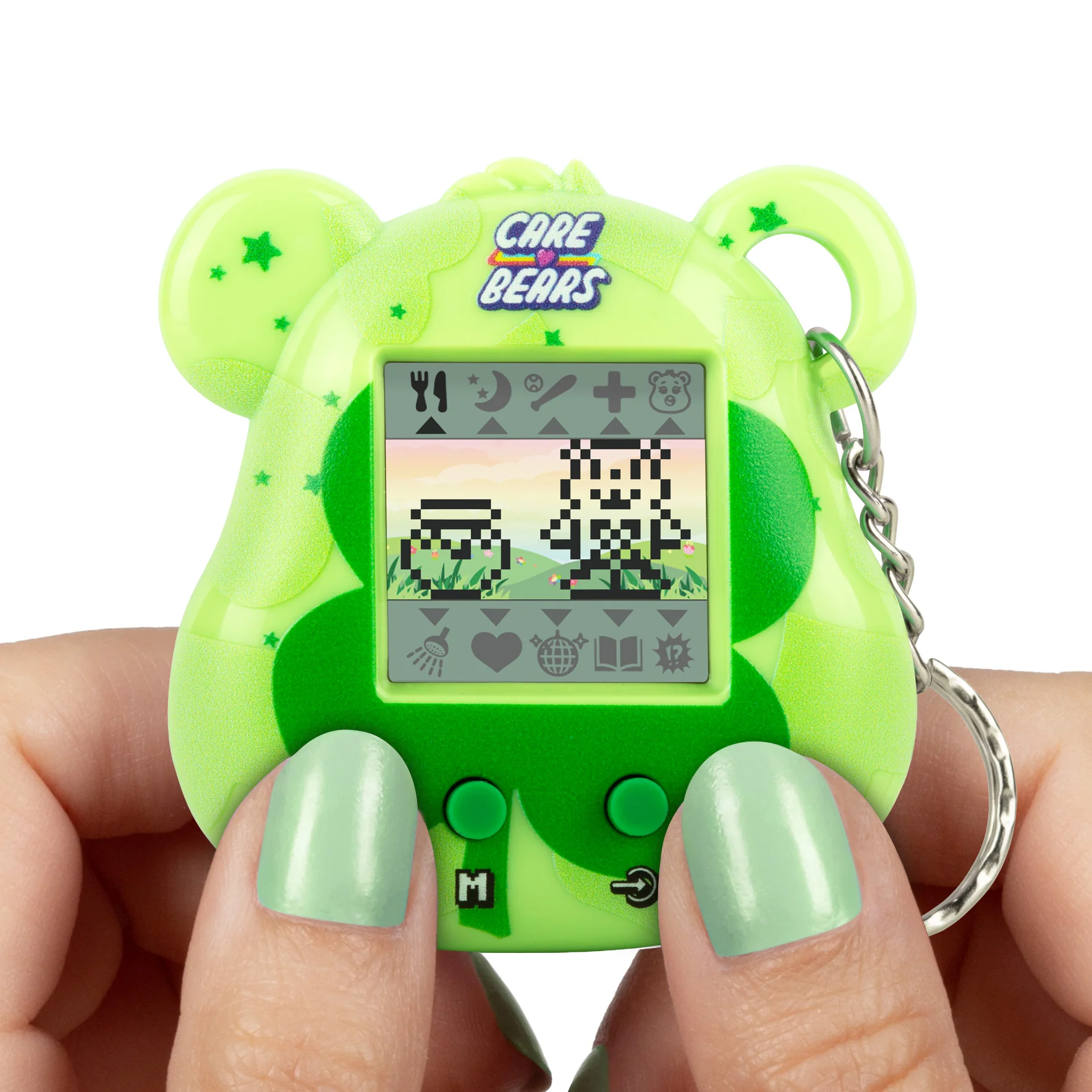 Een groen Care Bears elektronisch speelgoed met een scherm dat gepixelde karakters weergeeft. Vastgehouden door handen met groene nagellak.