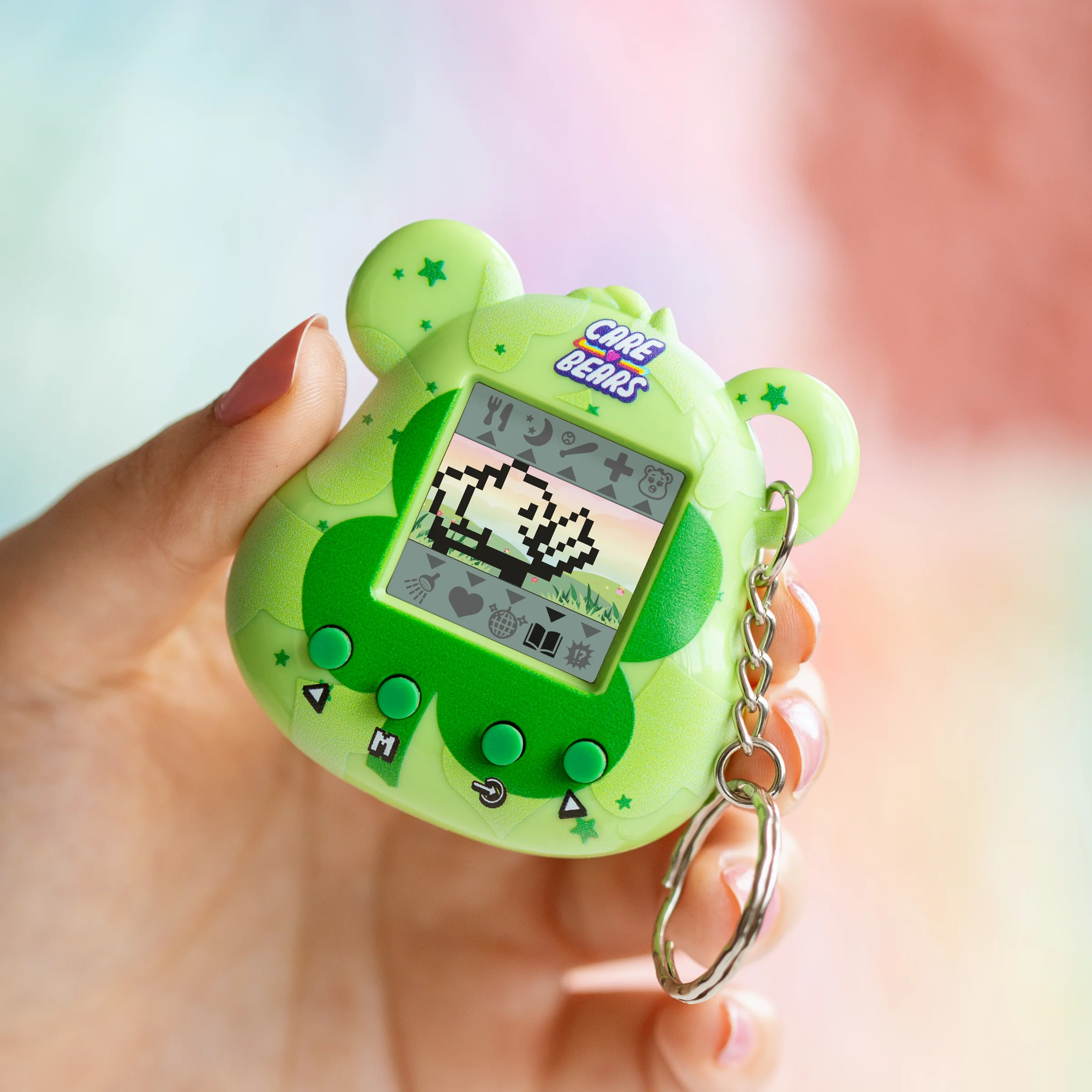 Een groen Care Bears-speeltje wordt vastgehouden. Het speeltje is een beer met een klein scherm met een pixelafbeelding.