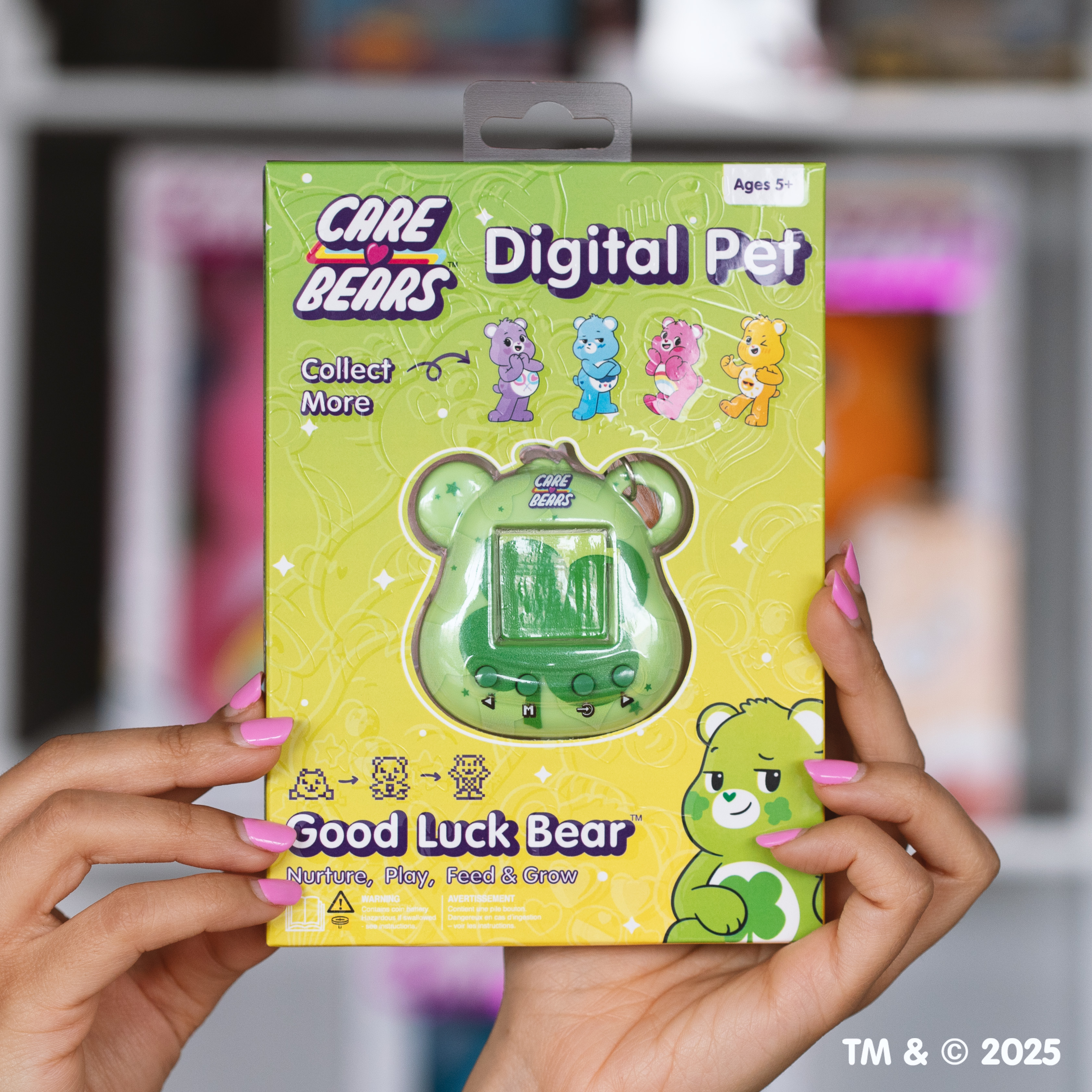 Een persoon houdt een Care Bears Digital Pet doos vast, met een groen, beer-vormig digitaal huisdier-apparaat.