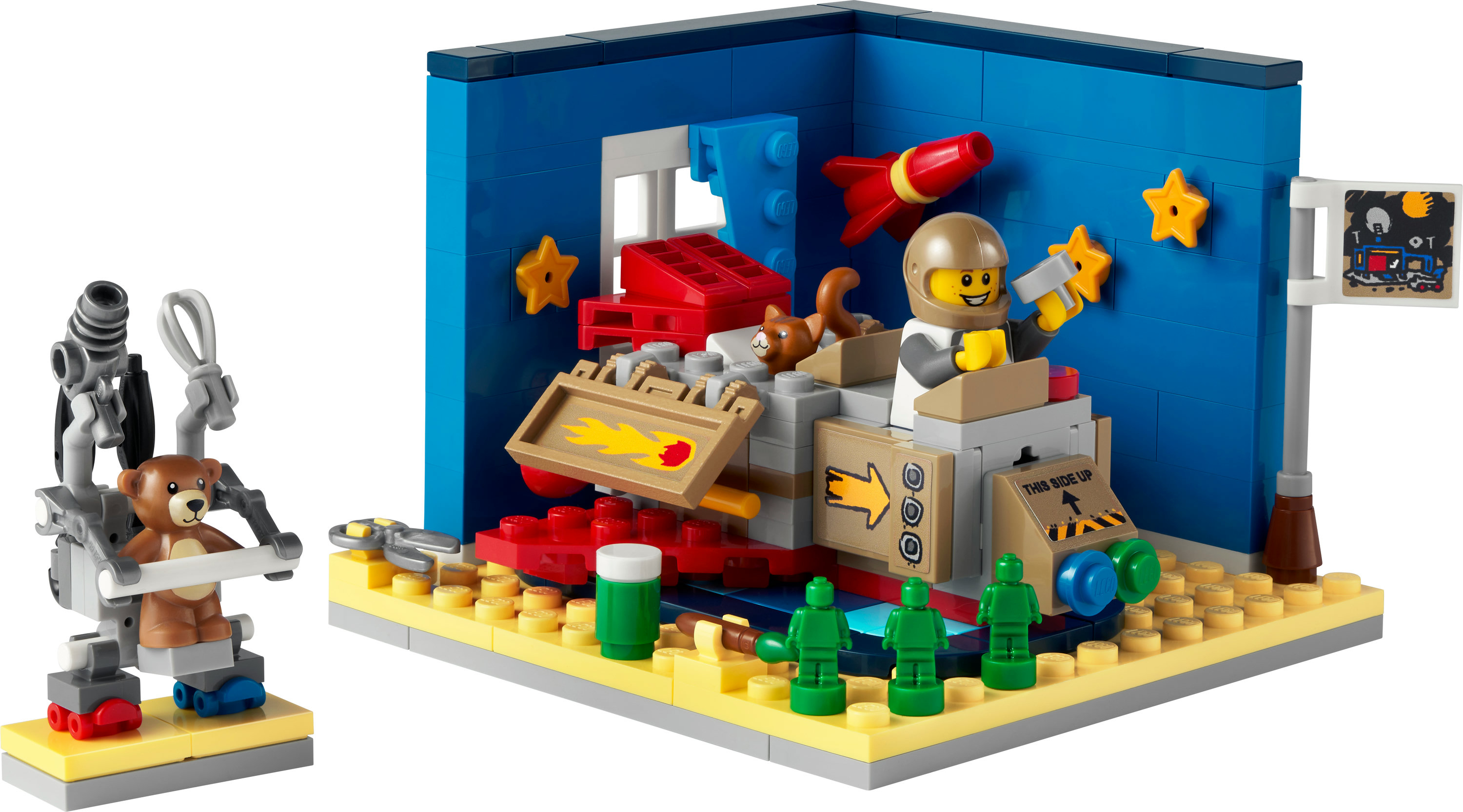 Bir Lego sahnesi, astronot, kedi ve roket içeren bir uzay gemisini, yıldızlarla dolu mavi bir duvarın önünde gösteriyor. Bir oyuncak ayı bir robotta oturuyor.