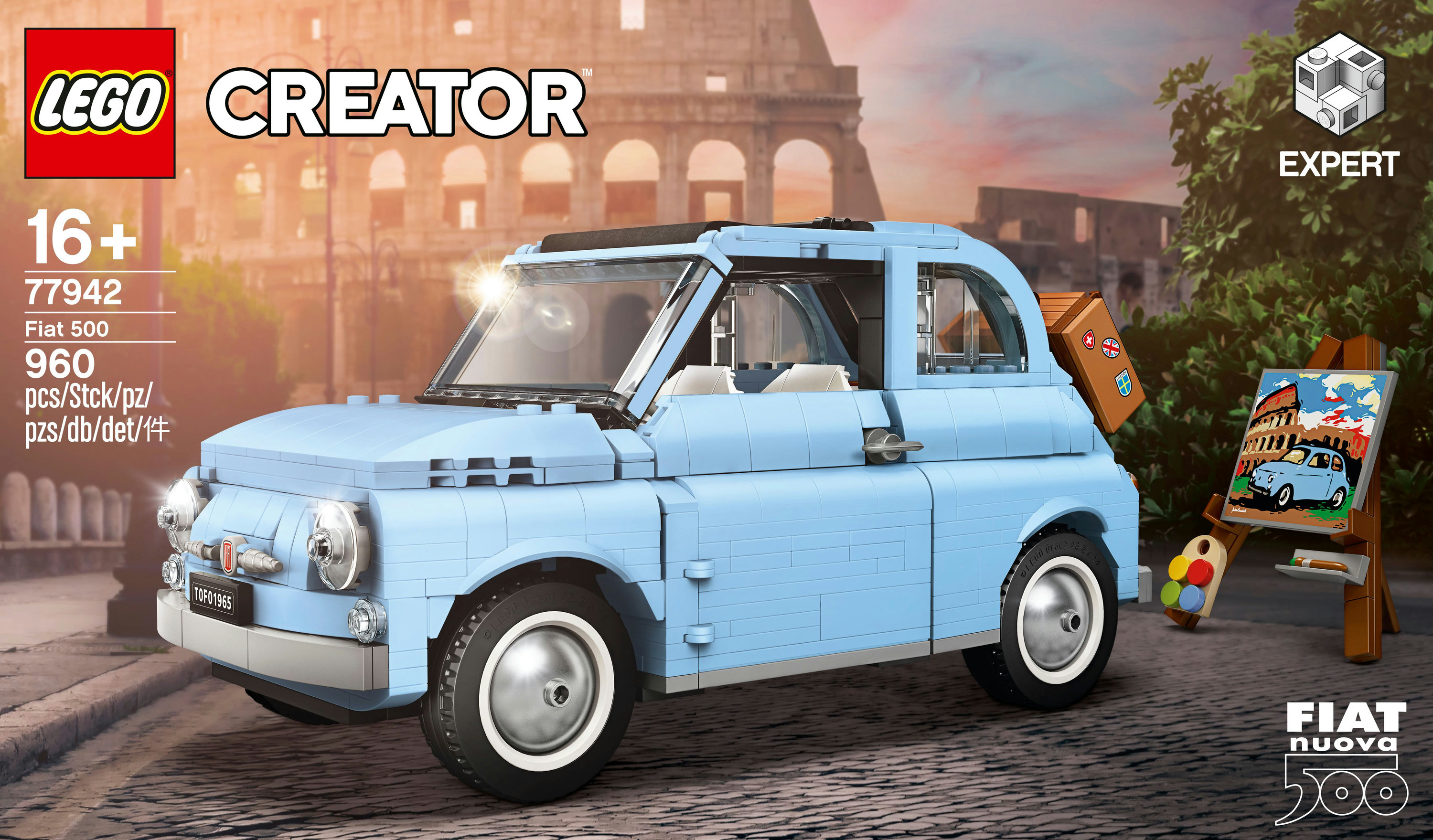 Bir Lego Creator Fiat 500 modeli. Açık mavi araba, bir resim ve bagaj ile Arnavut kaldırımlı bir yolda duruyor. Arka plan Roma manzarası.