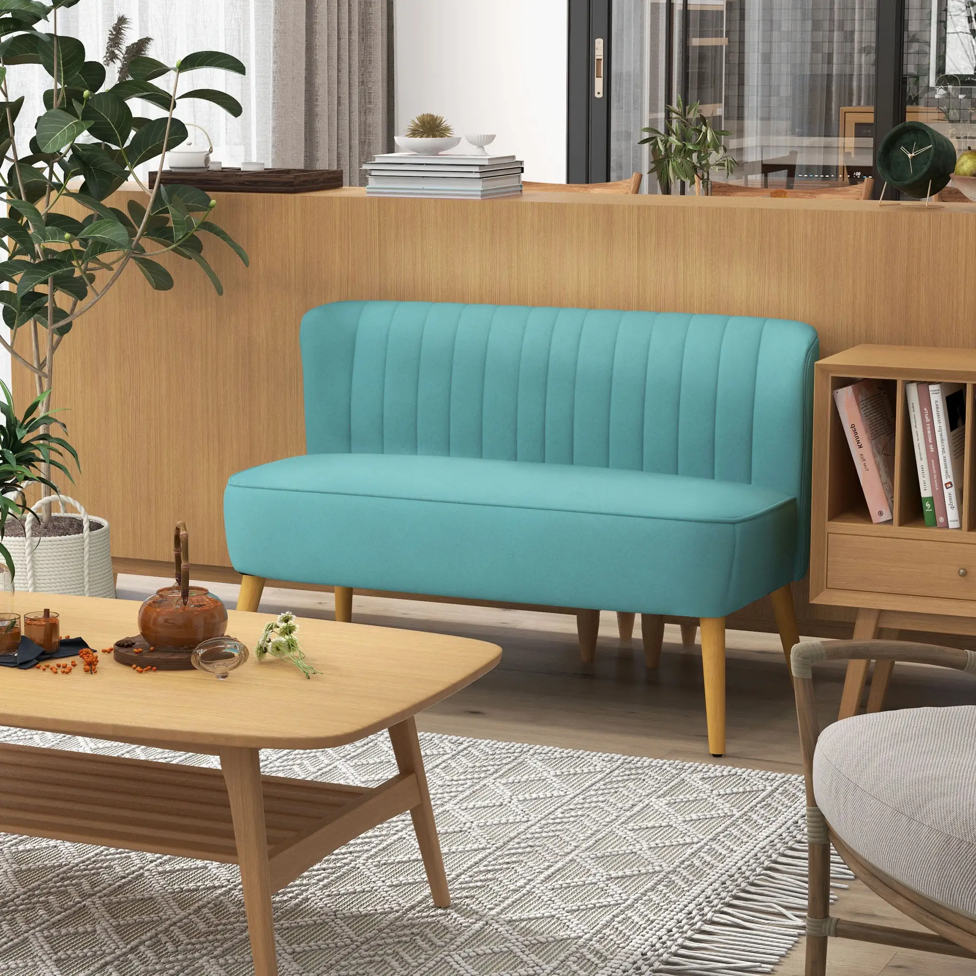 Ein türkisfarbenes Sofa steht in einem modernen Raum. Ein Holztisch trägt Tee und Blumen. Pflanzen und eine Uhr sind im Hintergrund.