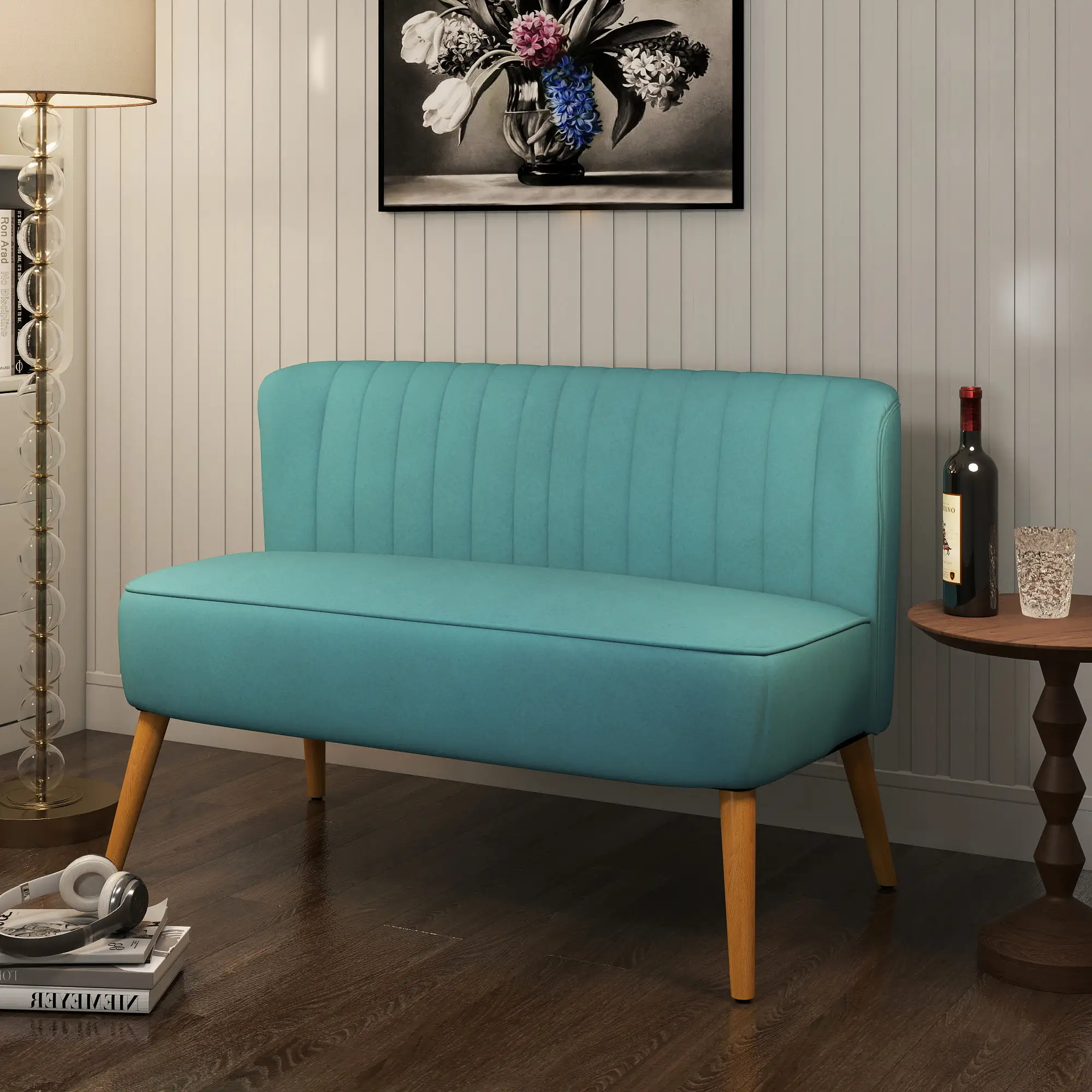 Ein türkisfarbenes Sofa mit Holzbeinen steht in einem Raum. Ein schwarz-weißes Blumenbild hängt darüber. Eine Flasche und ein Glas stehen auf einem Tisch.