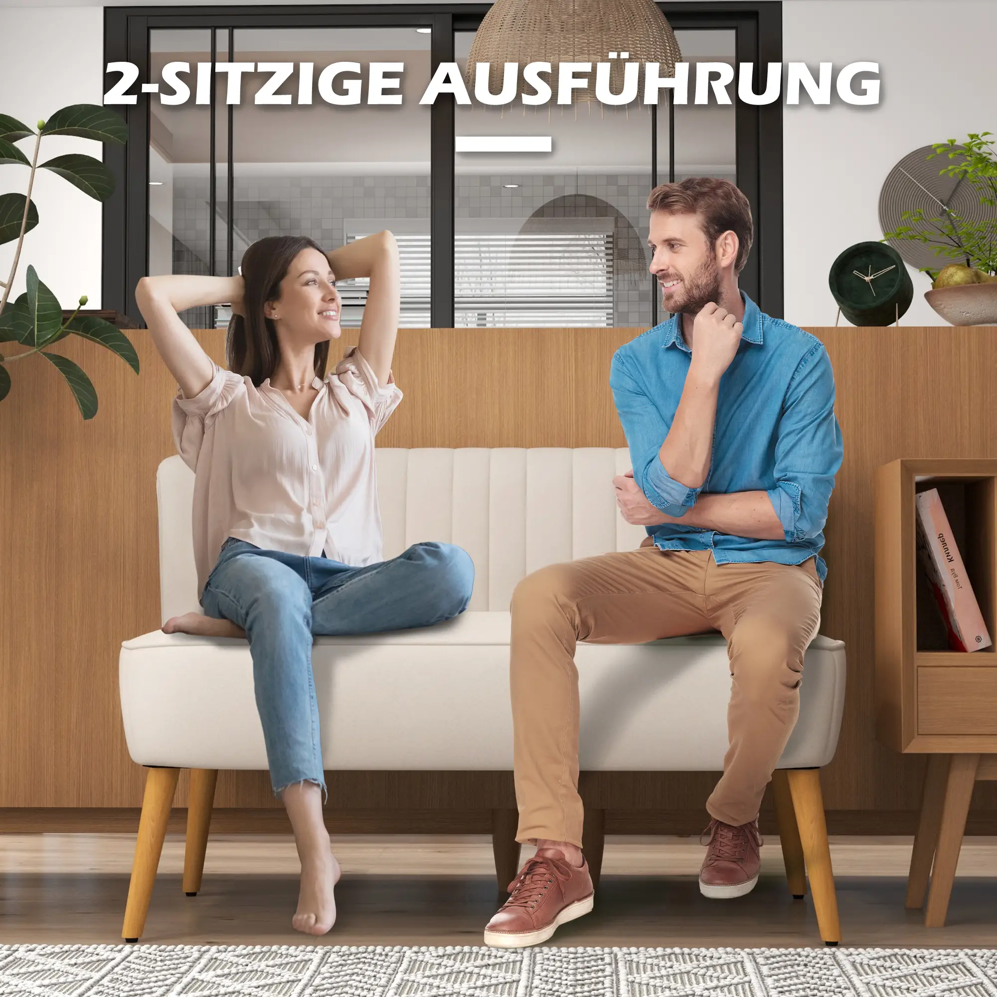 Ein Paar sitzt auf einem weißen Sofa. Die Frau hat die Arme erhoben. Der Mann stützt das Kinn auf die Hand und lächelt. Eine Uhr steht auf dem Regal.