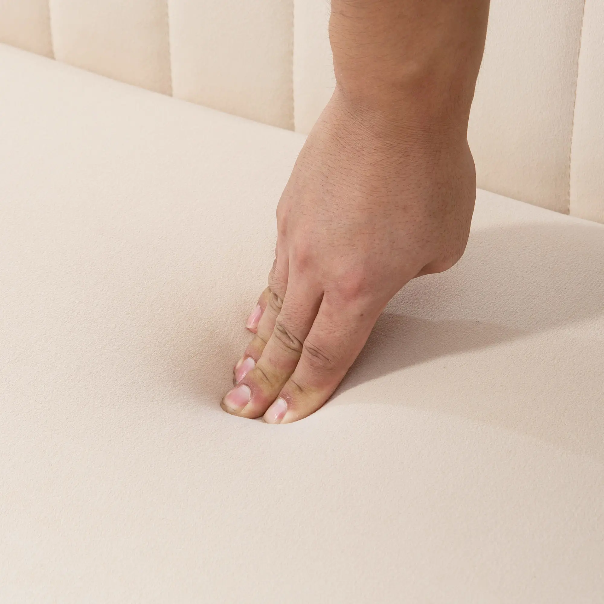 Eine Hand drückt auf eine cremefarbene Oberfläche. Die Oberfläche hat vertikale Rippen. Der Hautton der Hand ist hellbraun.