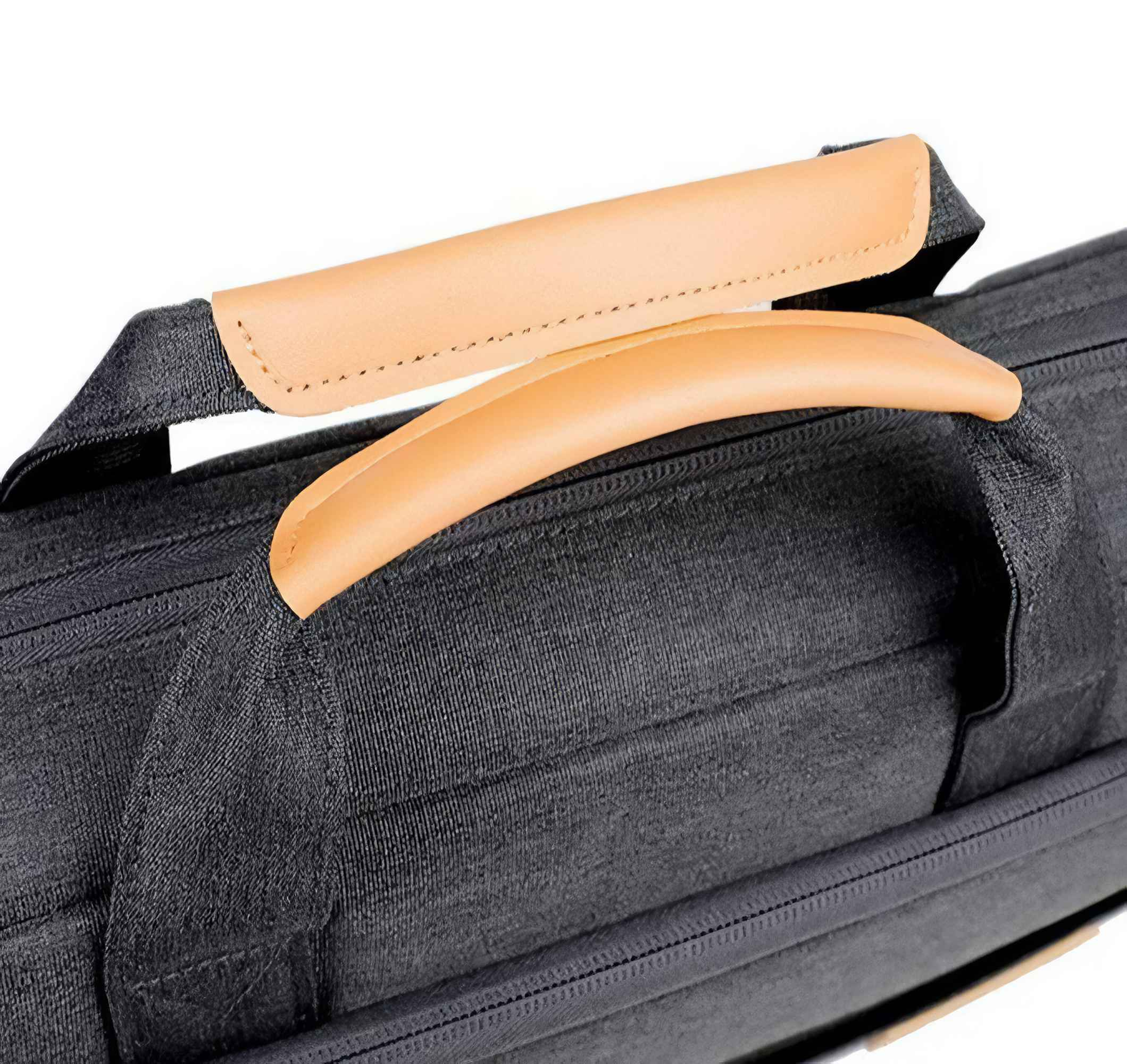 Nahaufnahme einer schwarzen Tasche mit einem hellbraunen Ledergriff. Der Griff ist gebogen und an der Tasche befestigt.